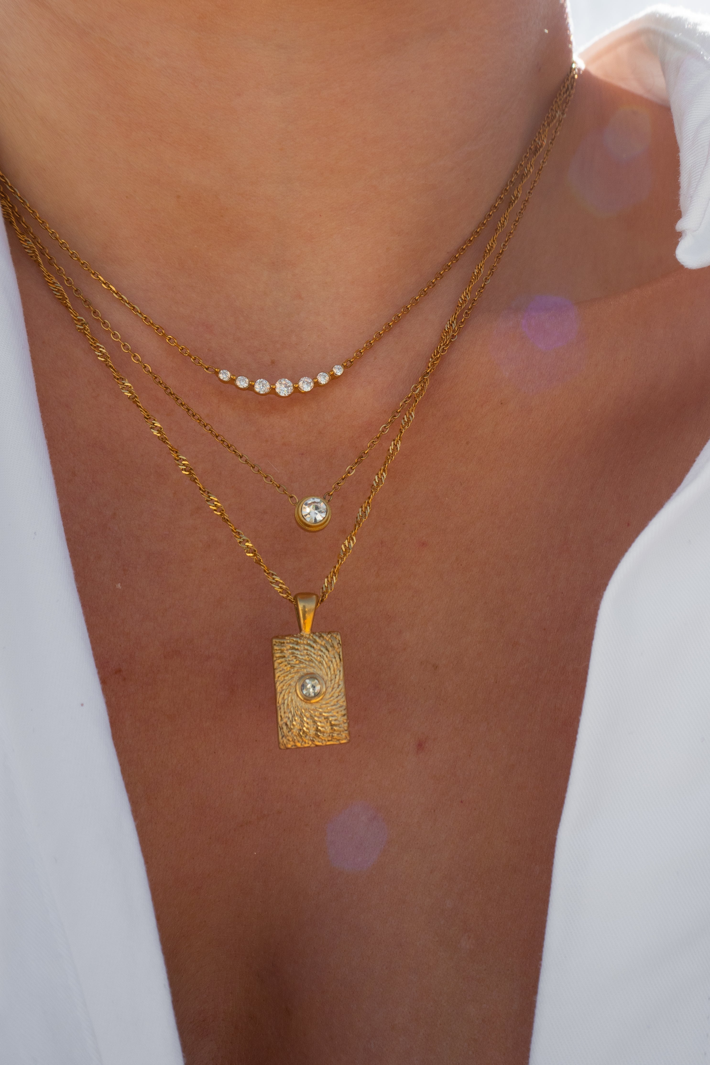 Close-up of a person wearing multiple gold necklaces with pendants.