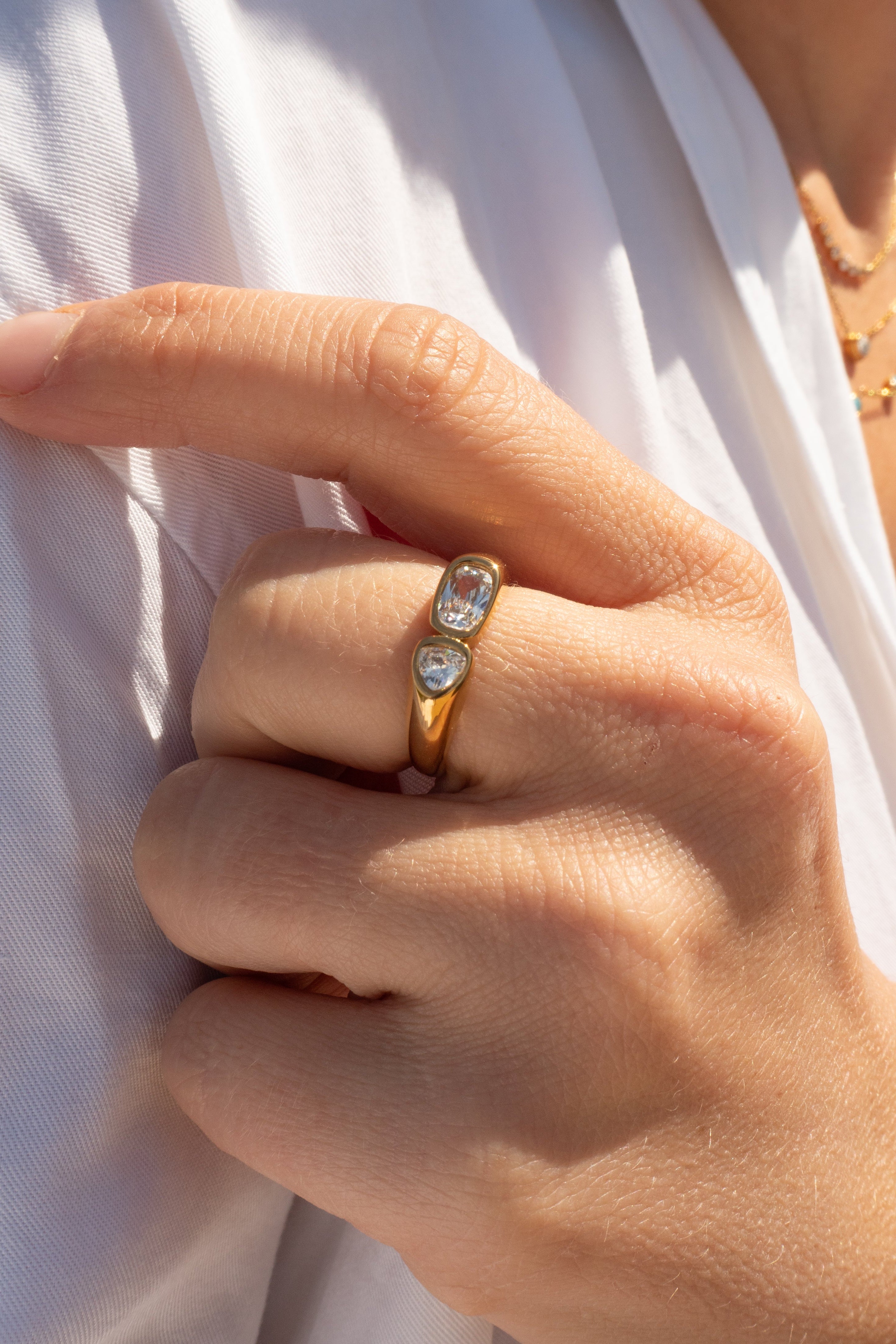 Close-up of a hand wearing a gold ring with three diamonds against a white background