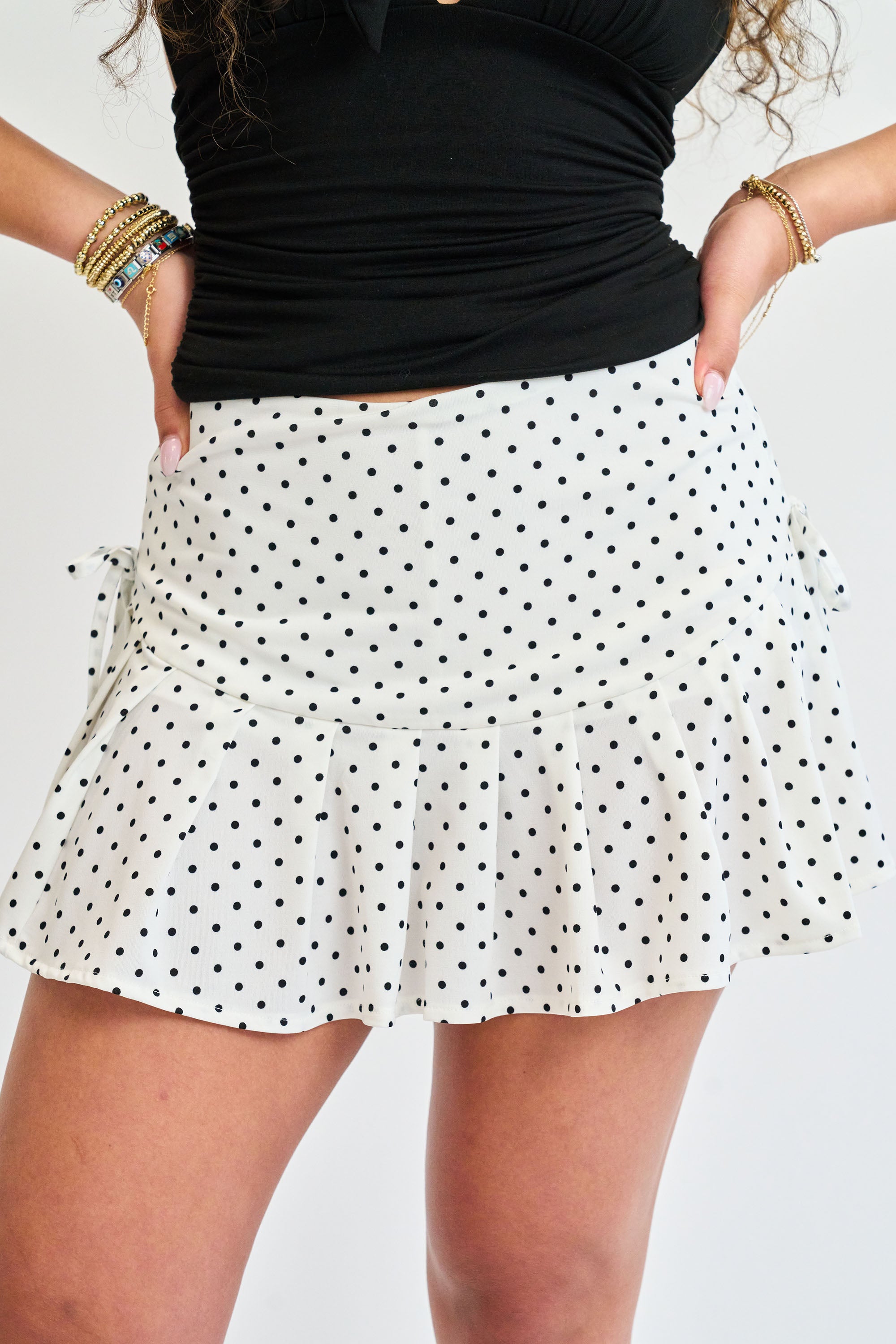 Person wearing a black top and white polka dot skirt on a plain background