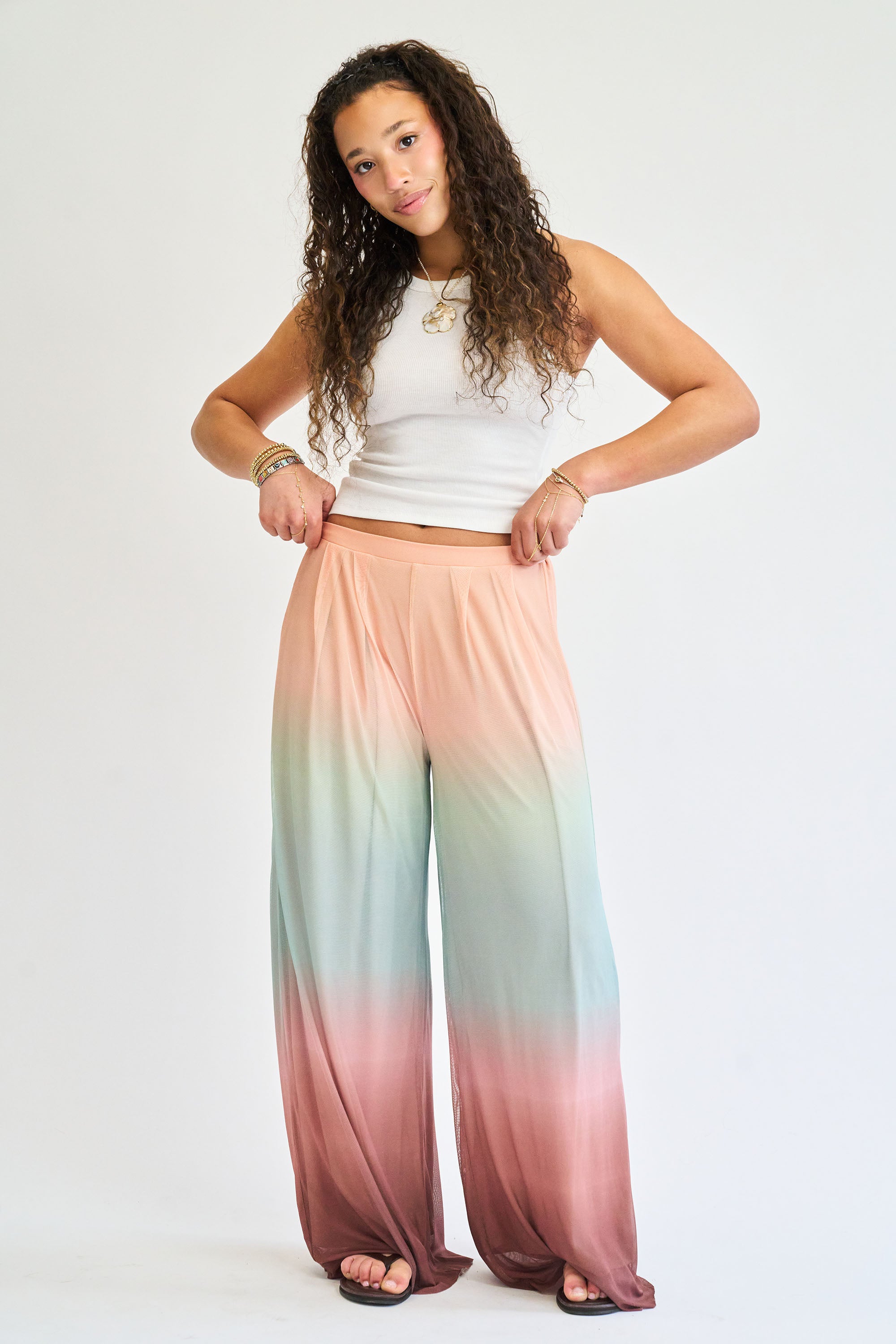 Woman wearing a white top and colorful gradient pants on a white background