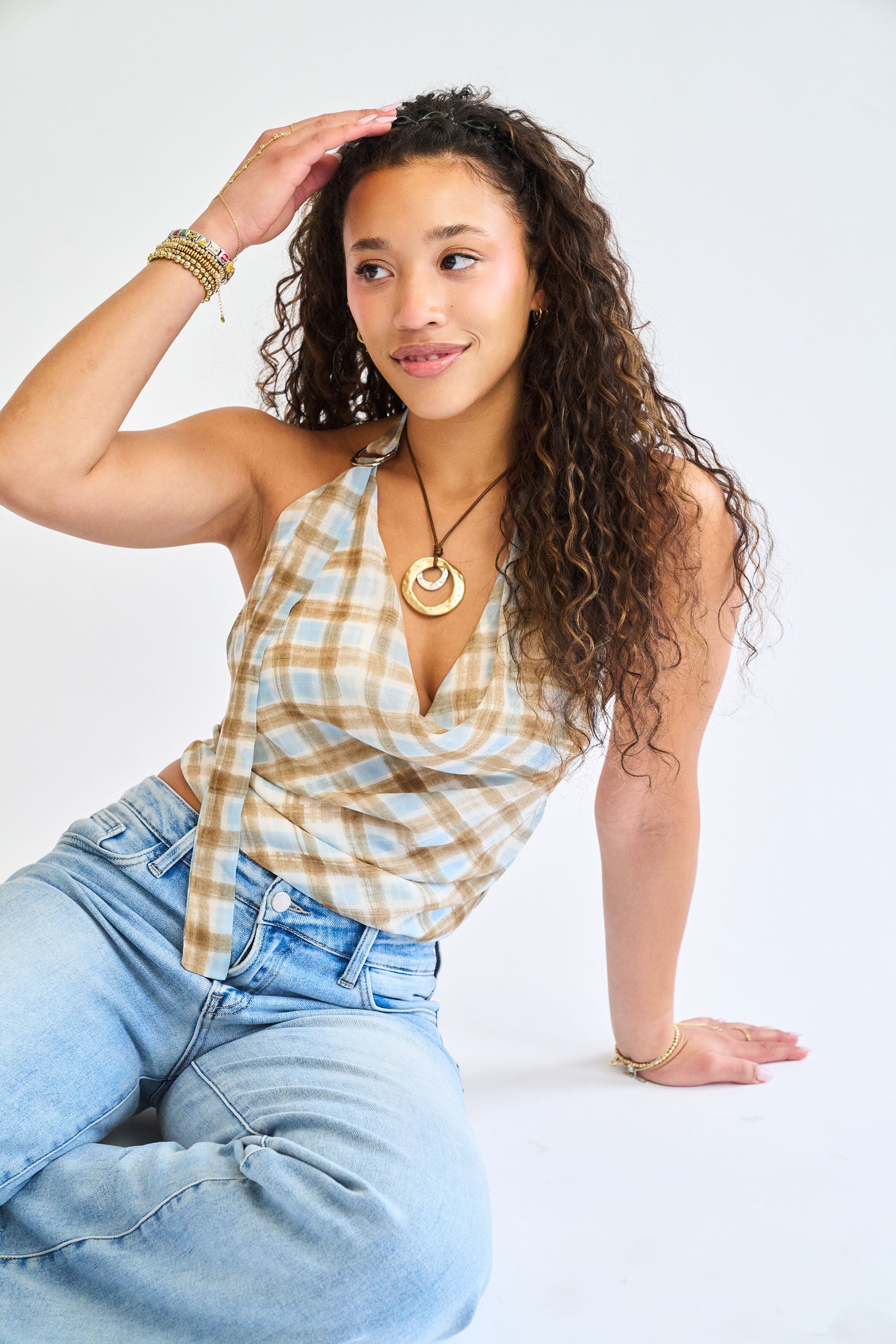 Woman wearing a plaid top and jeans with a plain background
