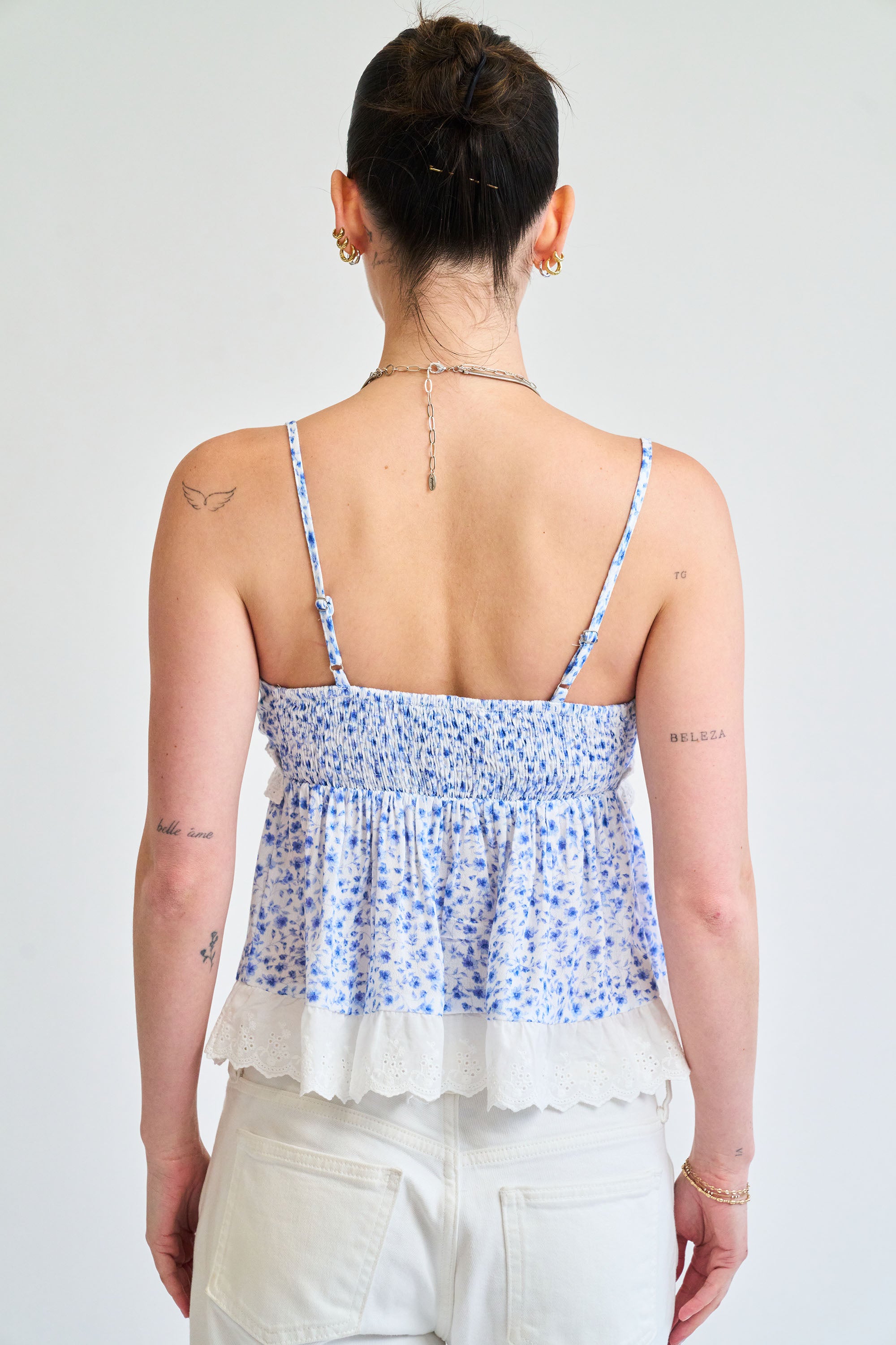 Person wearing a blue floral top with thin straps on a white background
