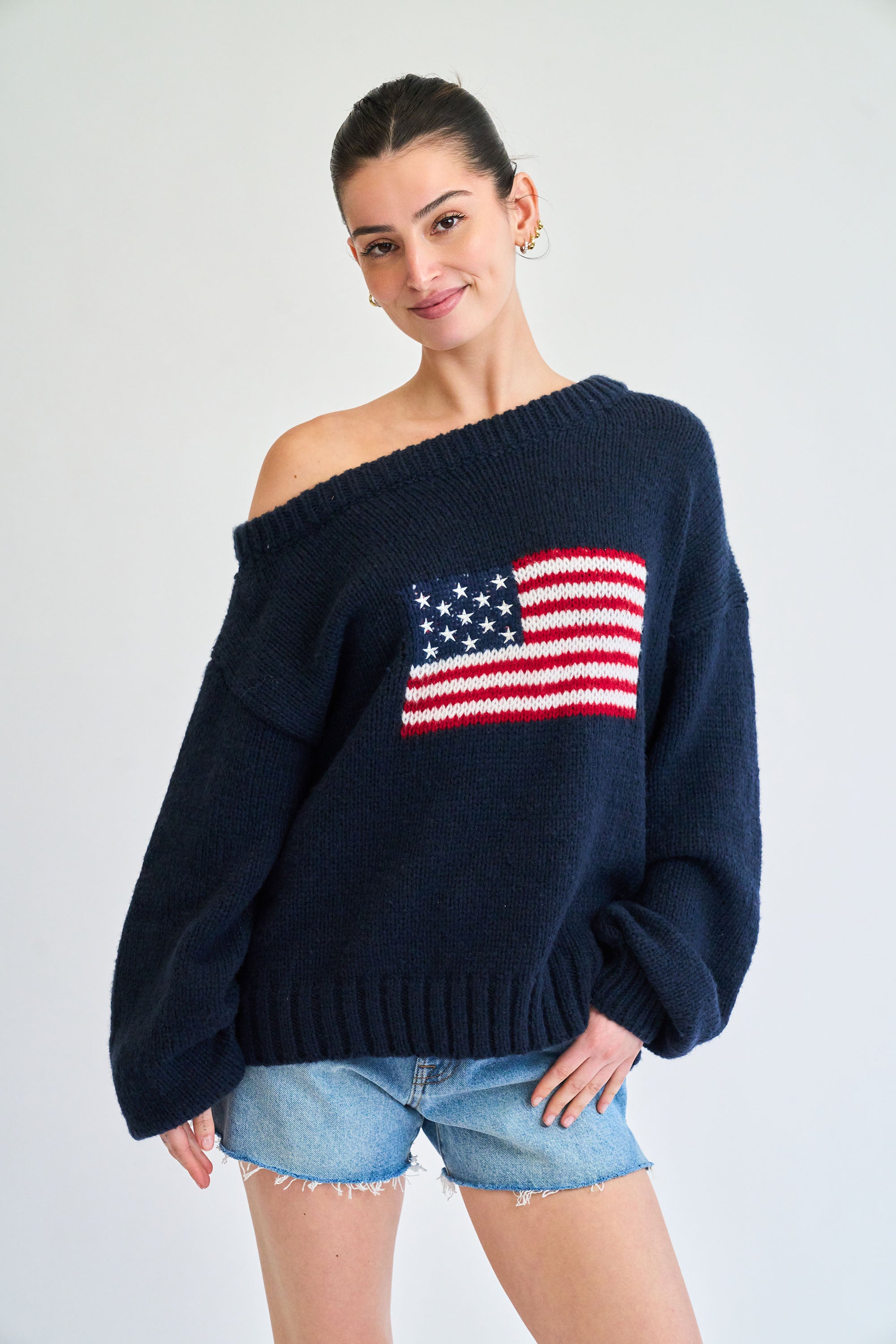 Woman wearing a navy blue sweater with an American flag design on a white background