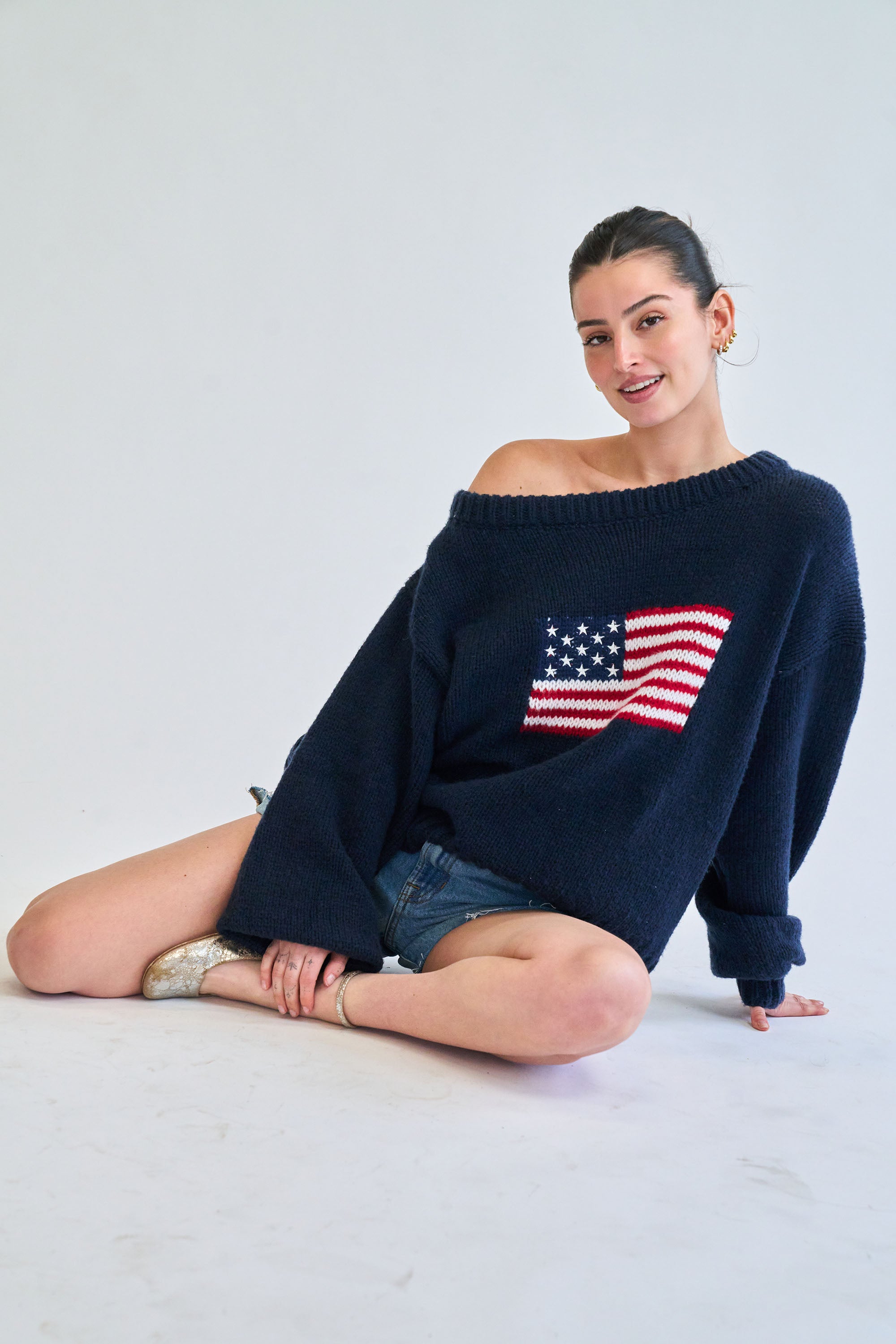 Woman wearing a navy blue sweater with an American flag design on a light gray background