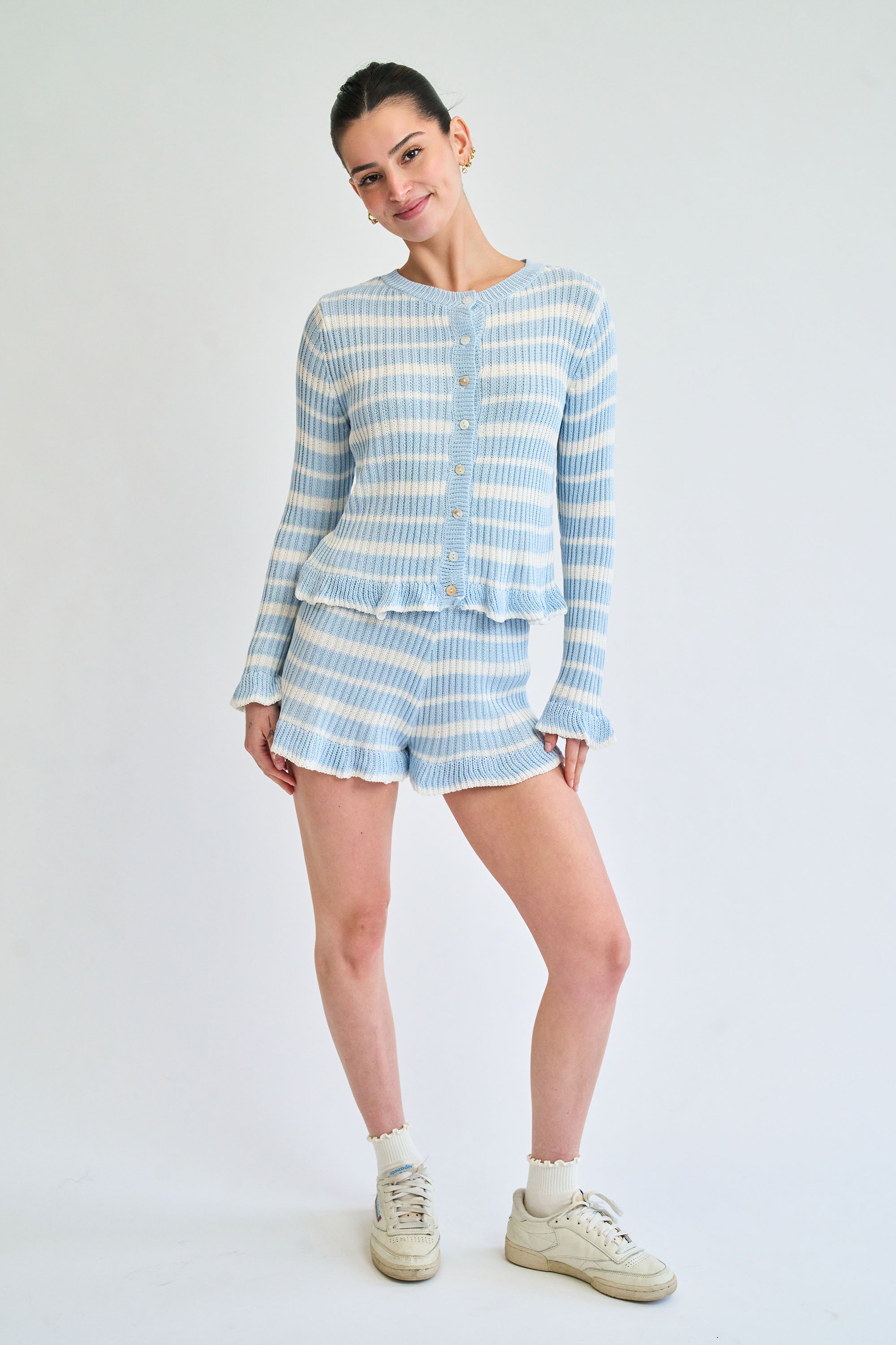 Woman wearing a blue and white striped outfit on a plain background