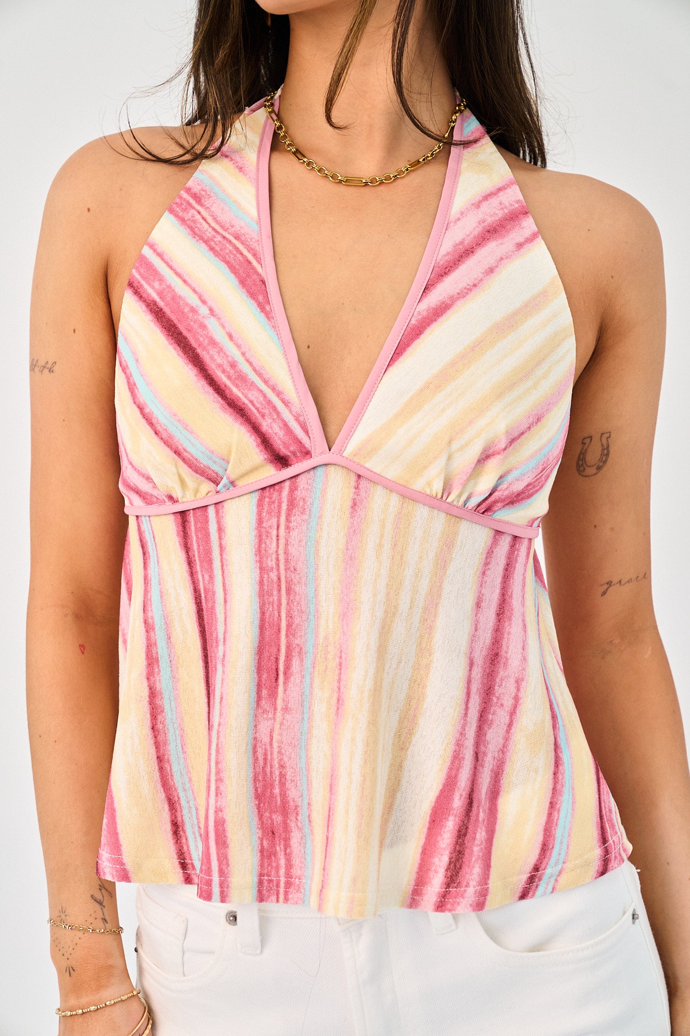 Woman wearing a colorful striped halter top against a white background