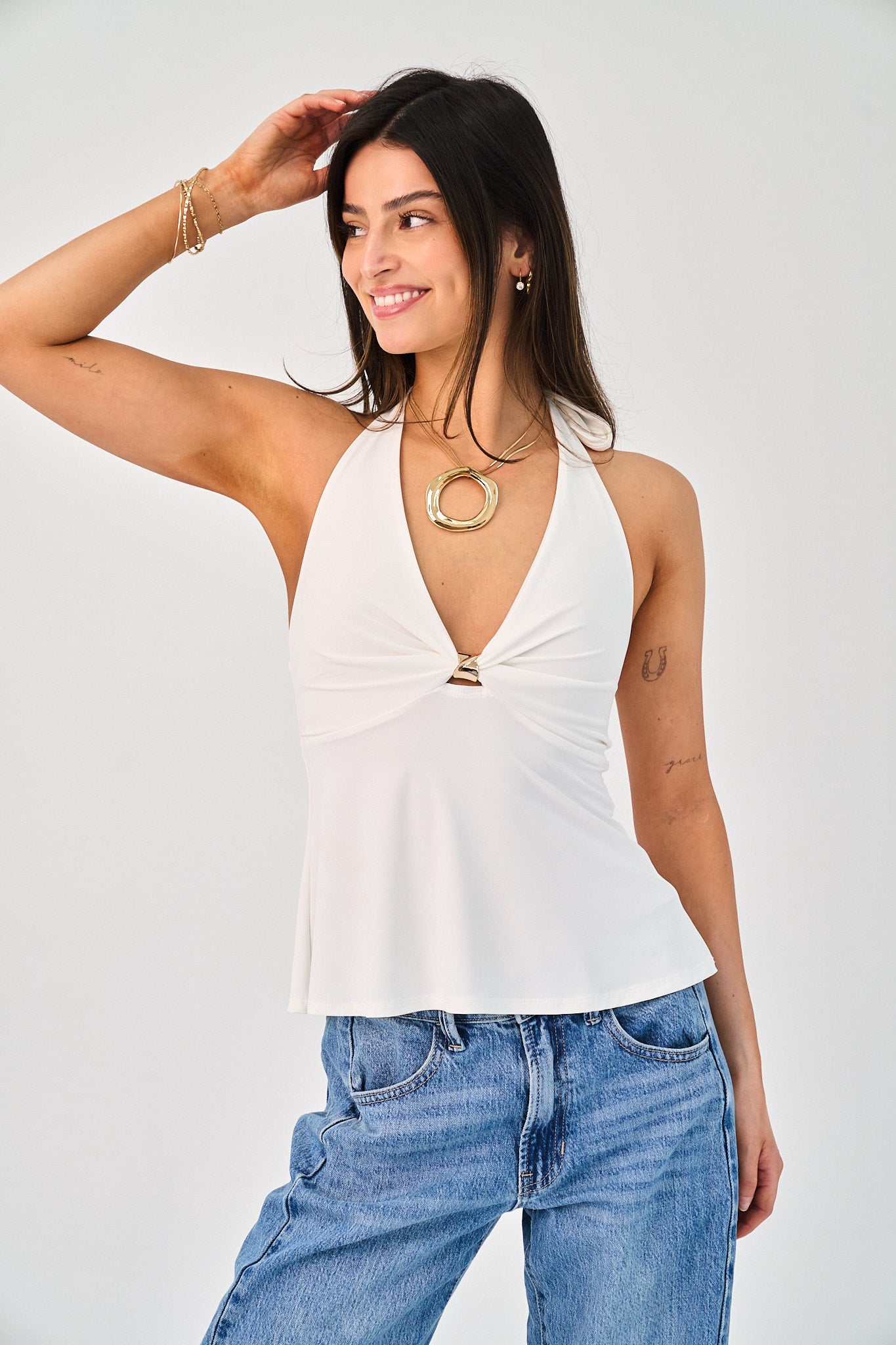 Woman wearing a white halter top and blue jeans on a plain background
