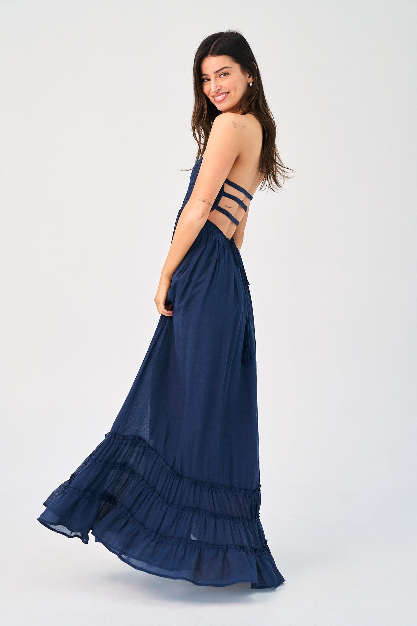 Woman wearing a navy blue dress with cut-out straps on a white background