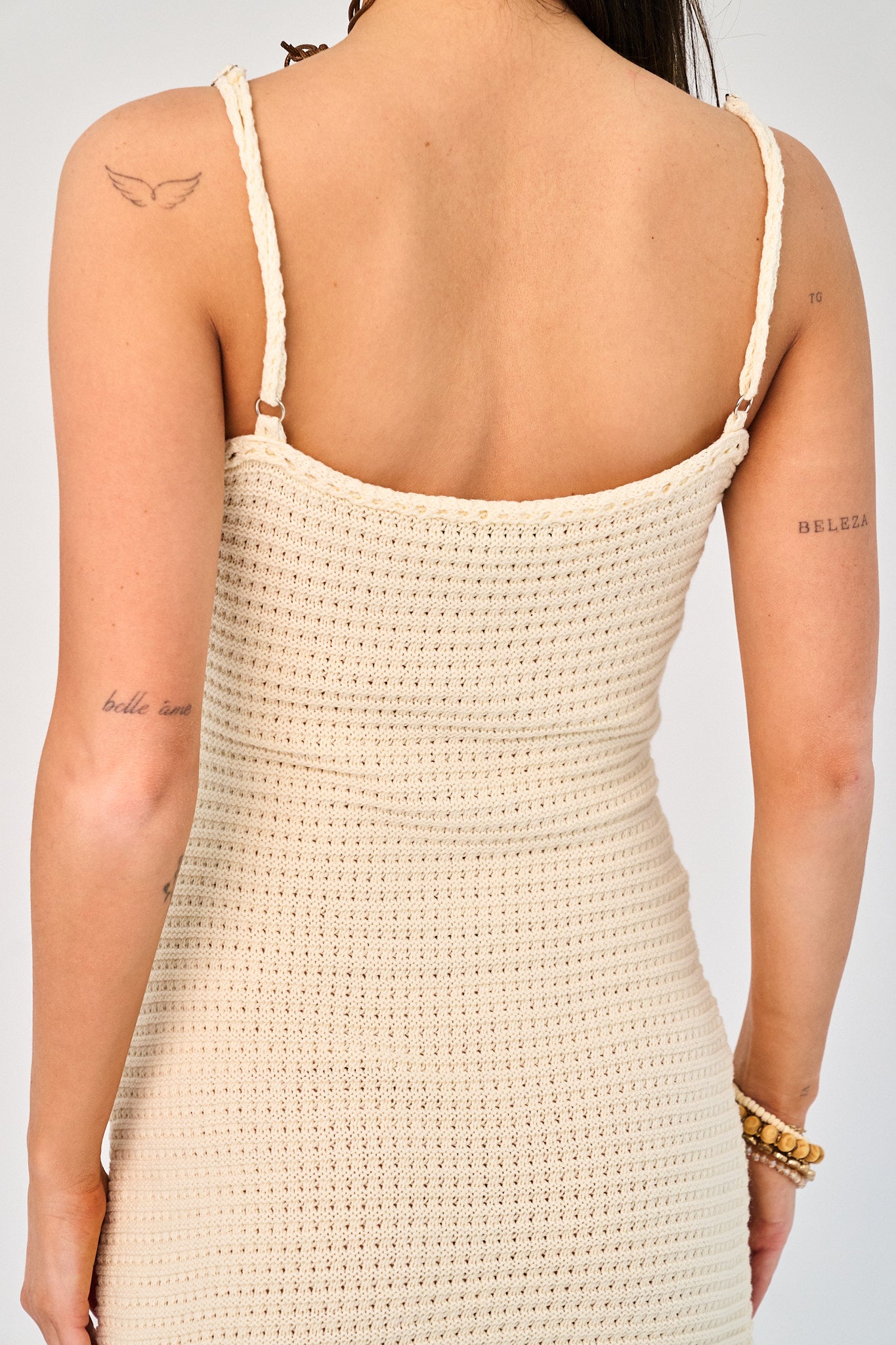 Beige crochet dress worn by a person on a plain background