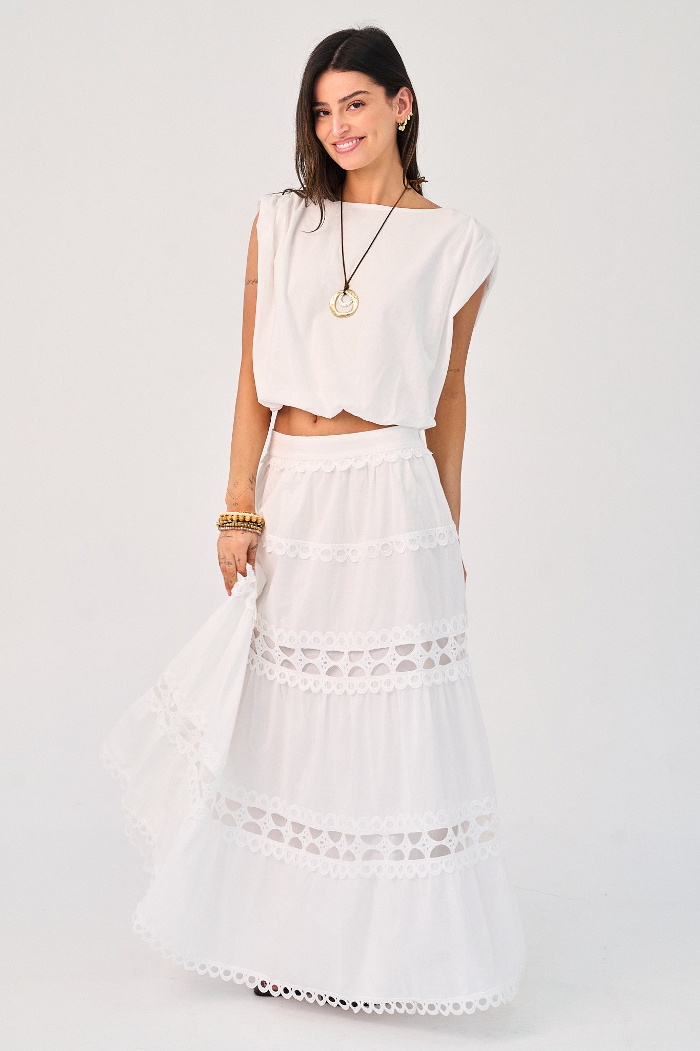 Woman wearing a white outfit with a lace skirt on a light gray background