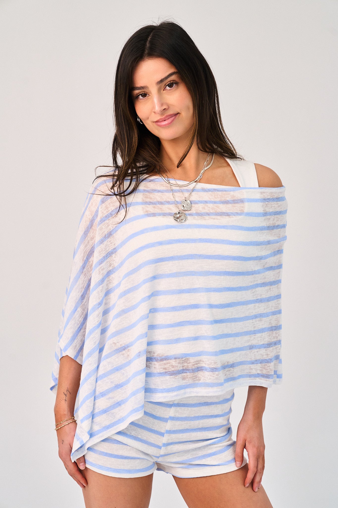 Woman wearing a blue and white striped top and shorts on a gray background