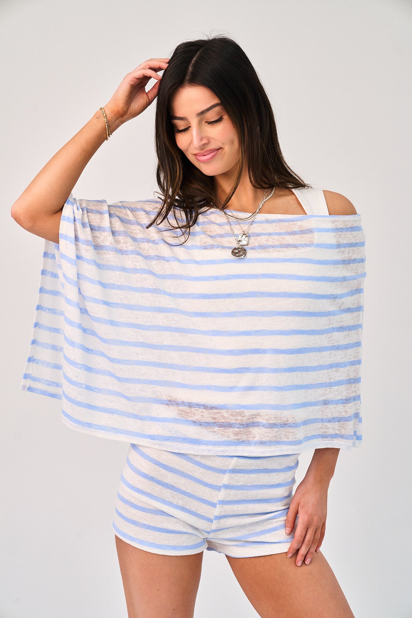 Woman wearing a light blue and white striped top and shorts on a plain background