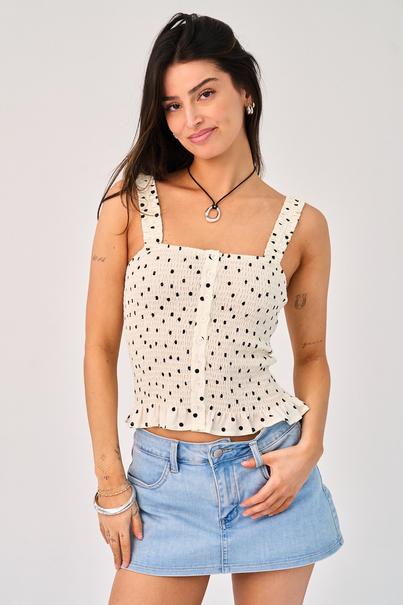 Woman wearing a polka dot top and denim skirt on a plain background