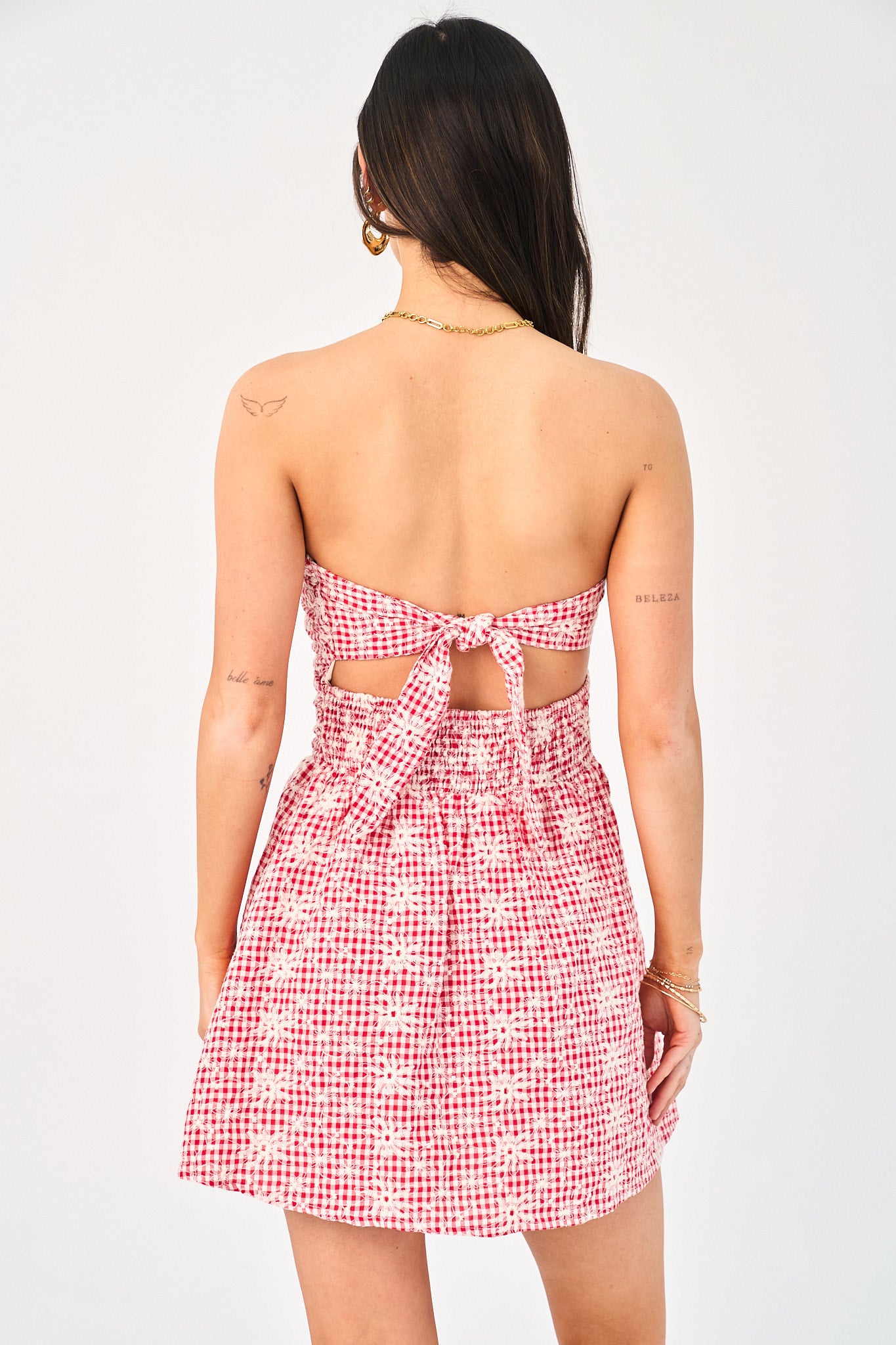 Woman wearing a red and white checkered dress with cut-out design on a white background