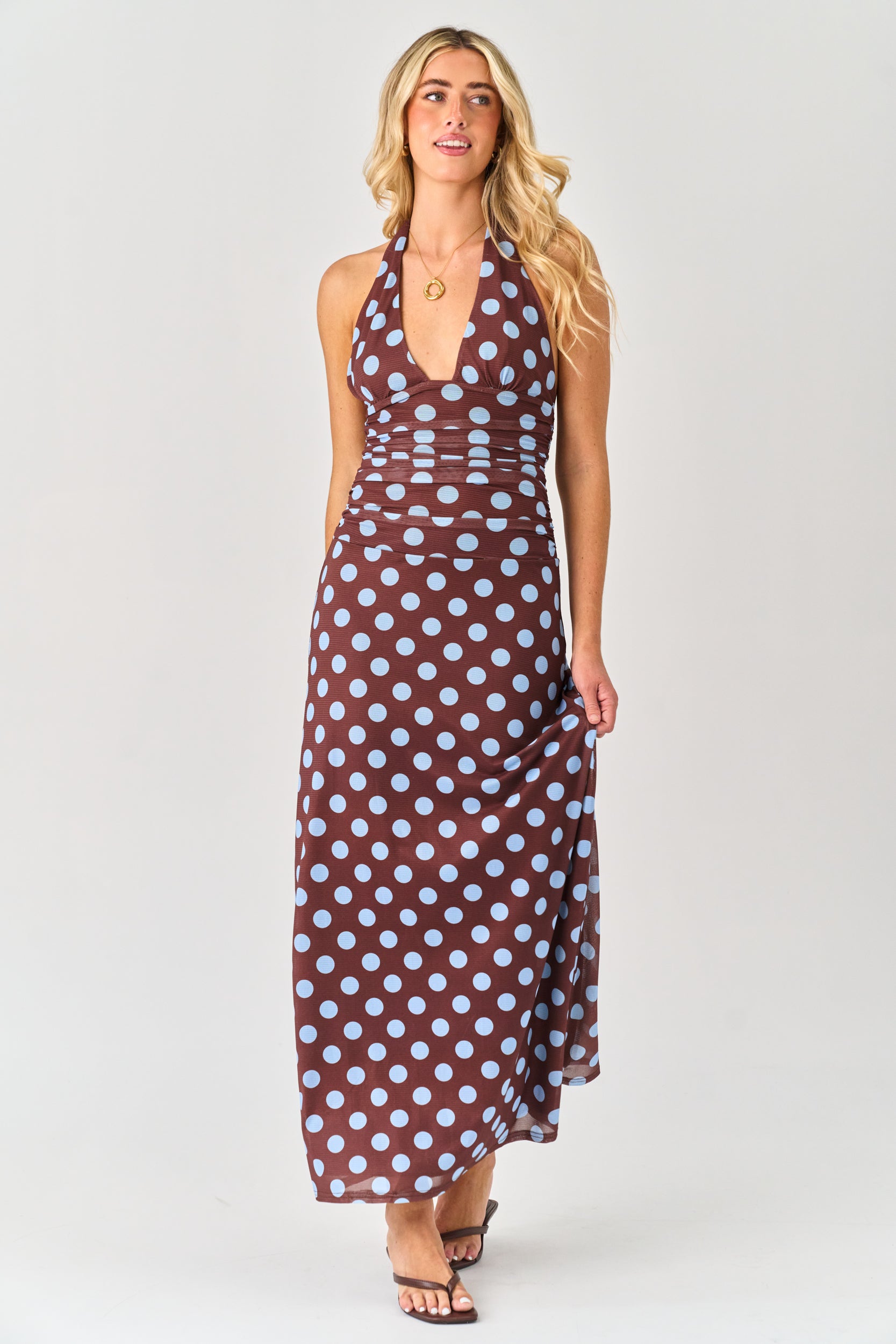 Woman wearing a brown dress with white polka dots on a white background