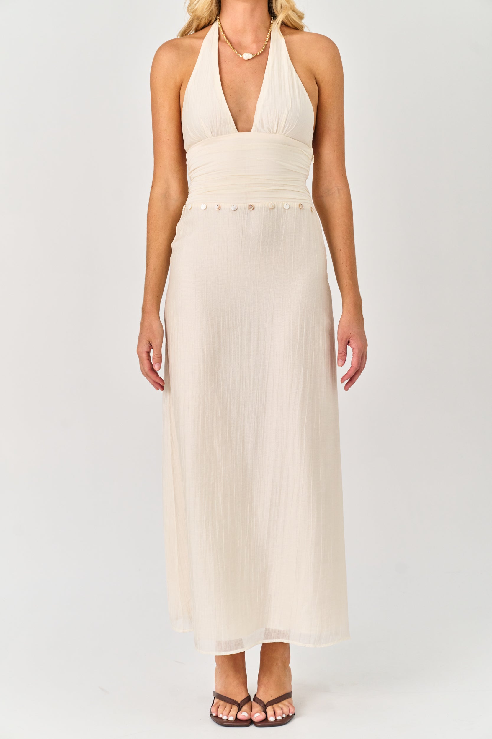 Woman wearing a white halter neck dress on a plain background