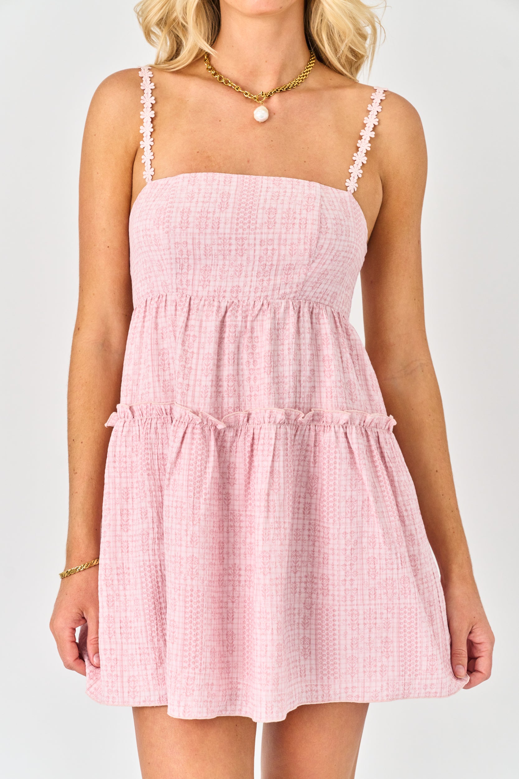 Pink checkered dress worn by a person on a white background