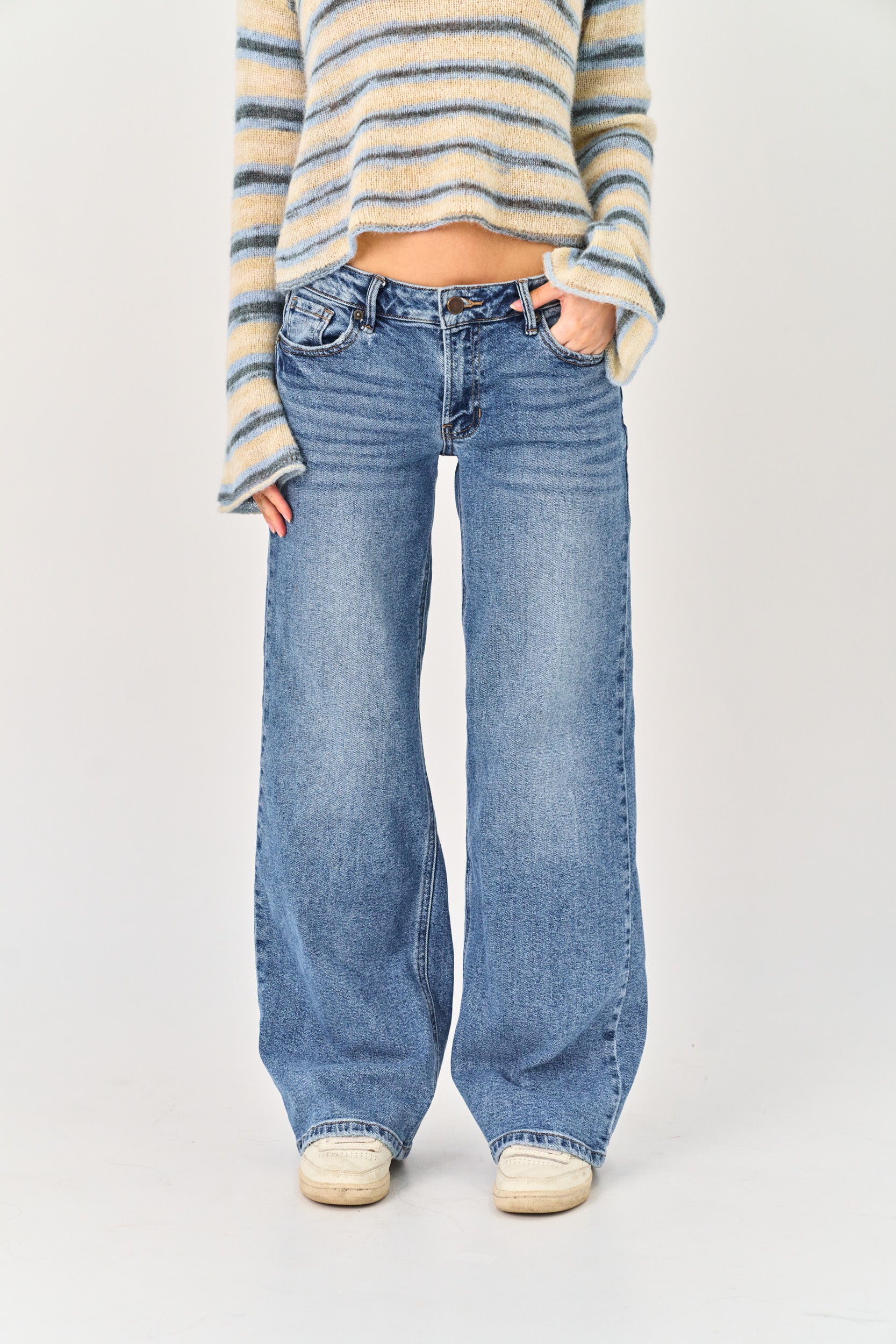 Person wearing a striped sweater and blue jeans on a white background