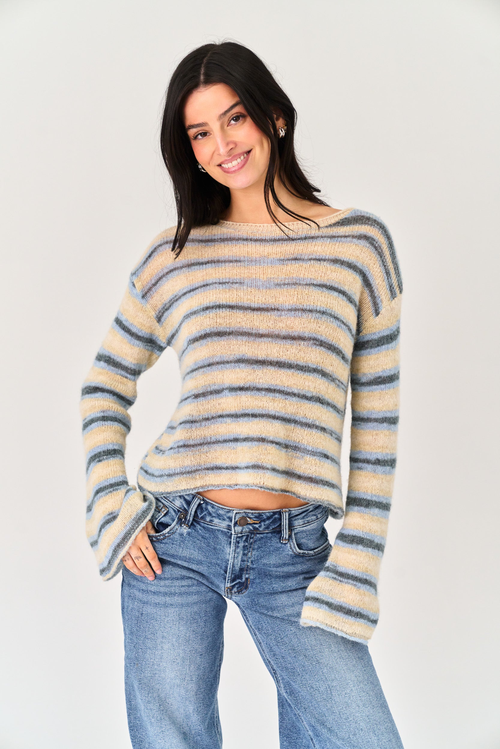 Woman wearing a striped sweater and jeans on a plain background