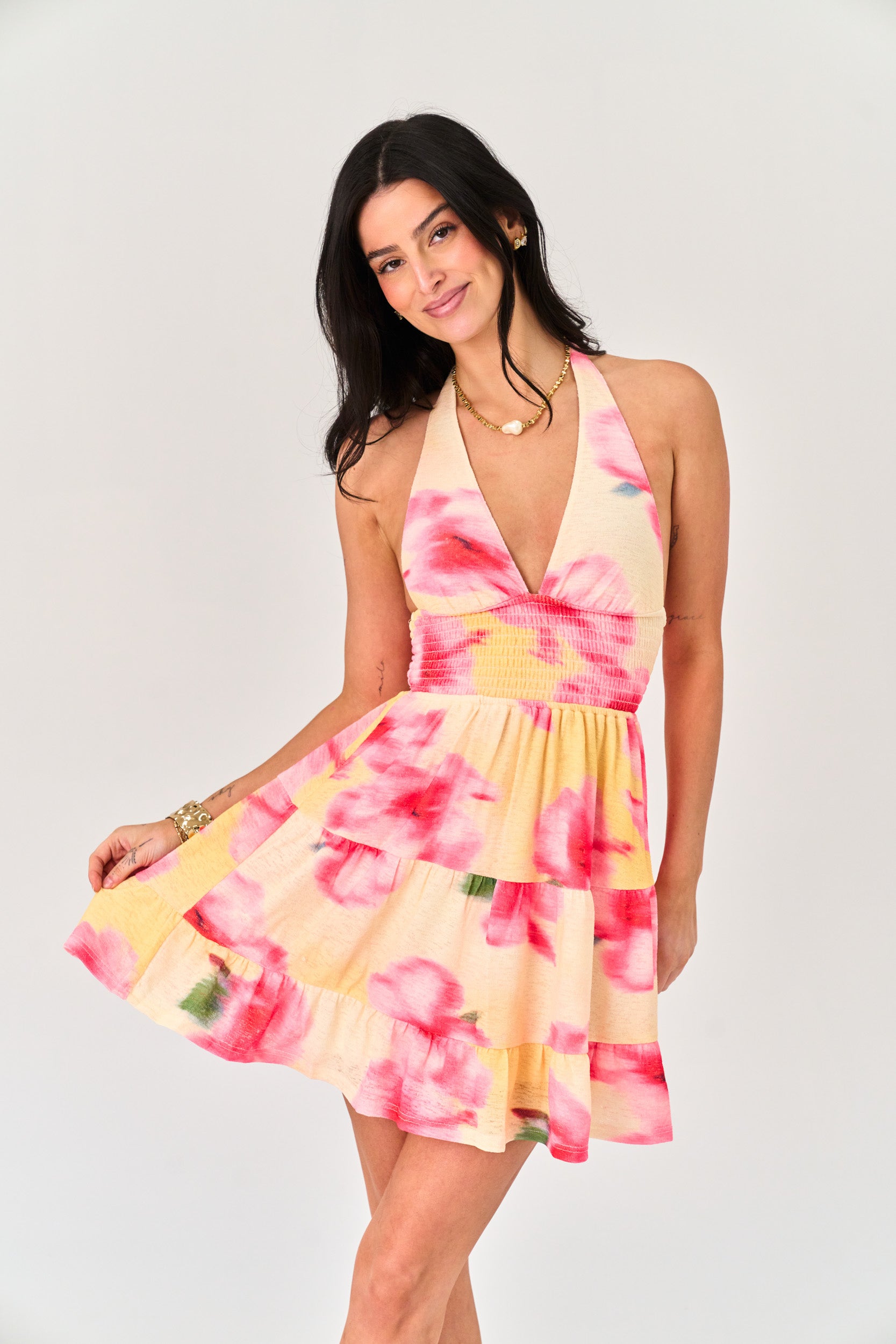 Woman wearing a pink and yellow floral dress on a white background