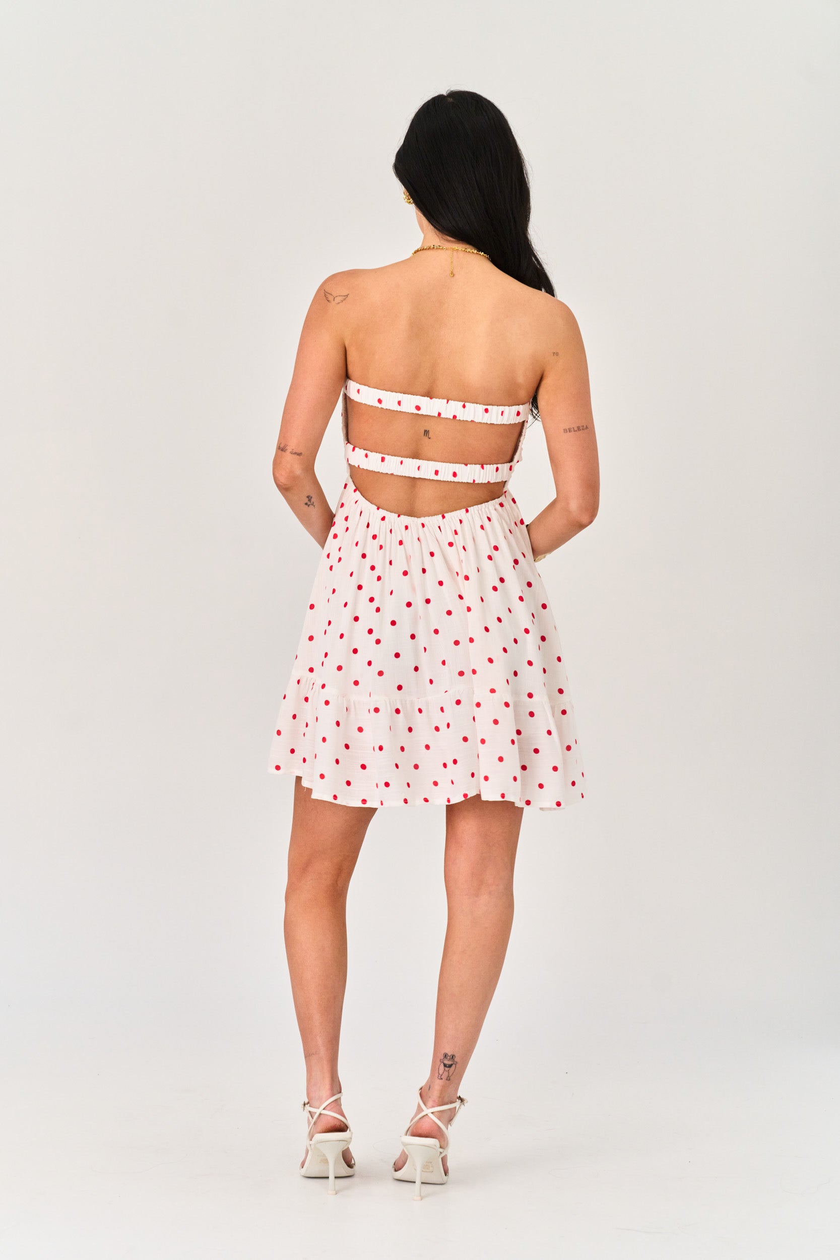 Woman wearing a white dress with red patterns on a plain background