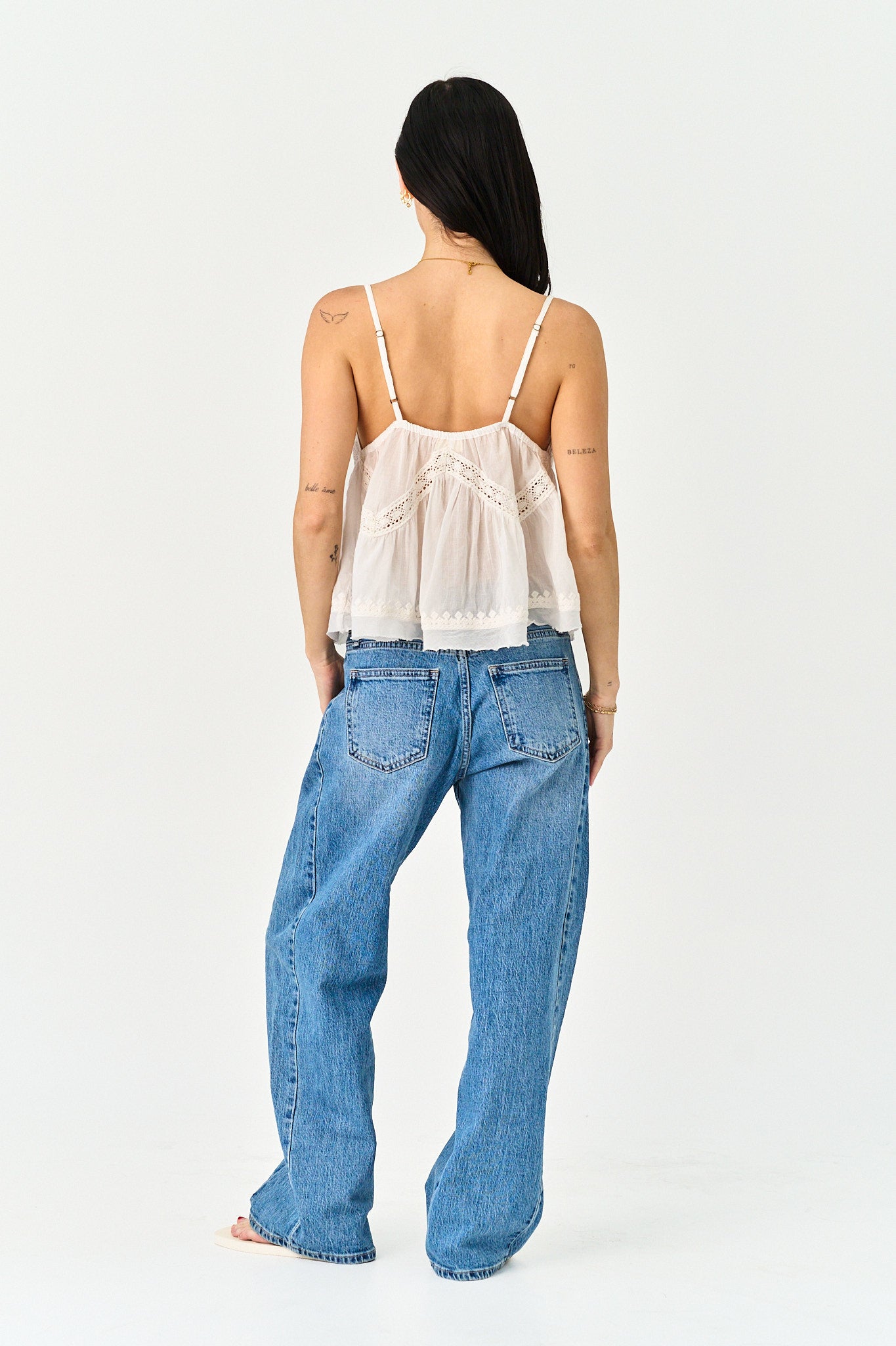 Person wearing a white top and blue jeans on a white background