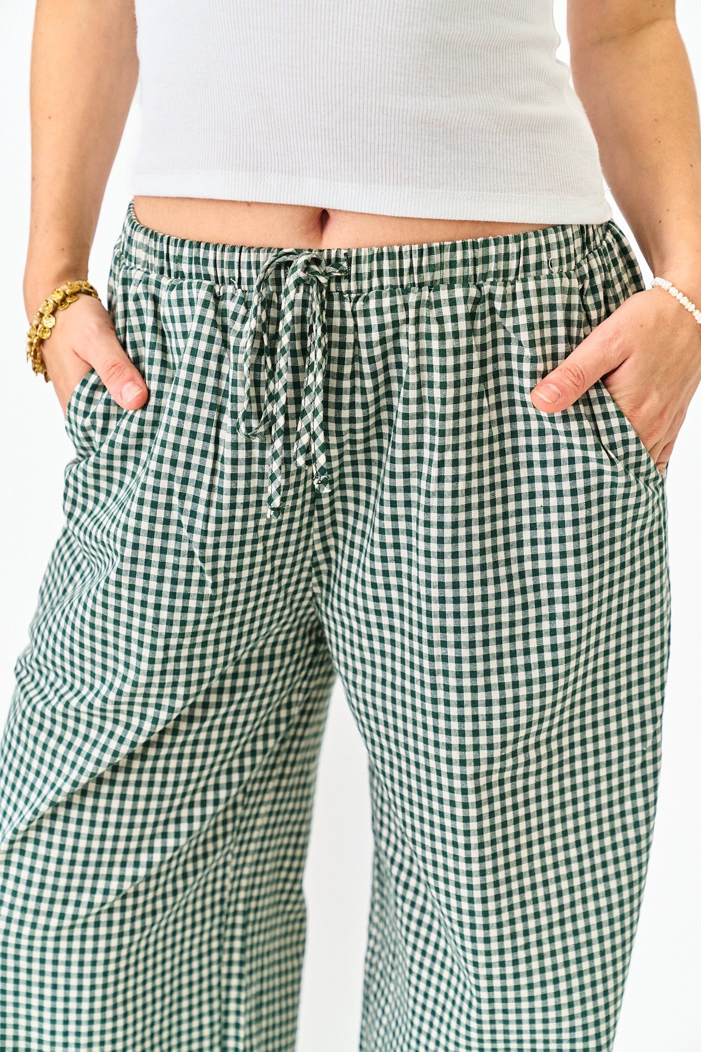 Green and white checkered pants worn by a person on a plain background