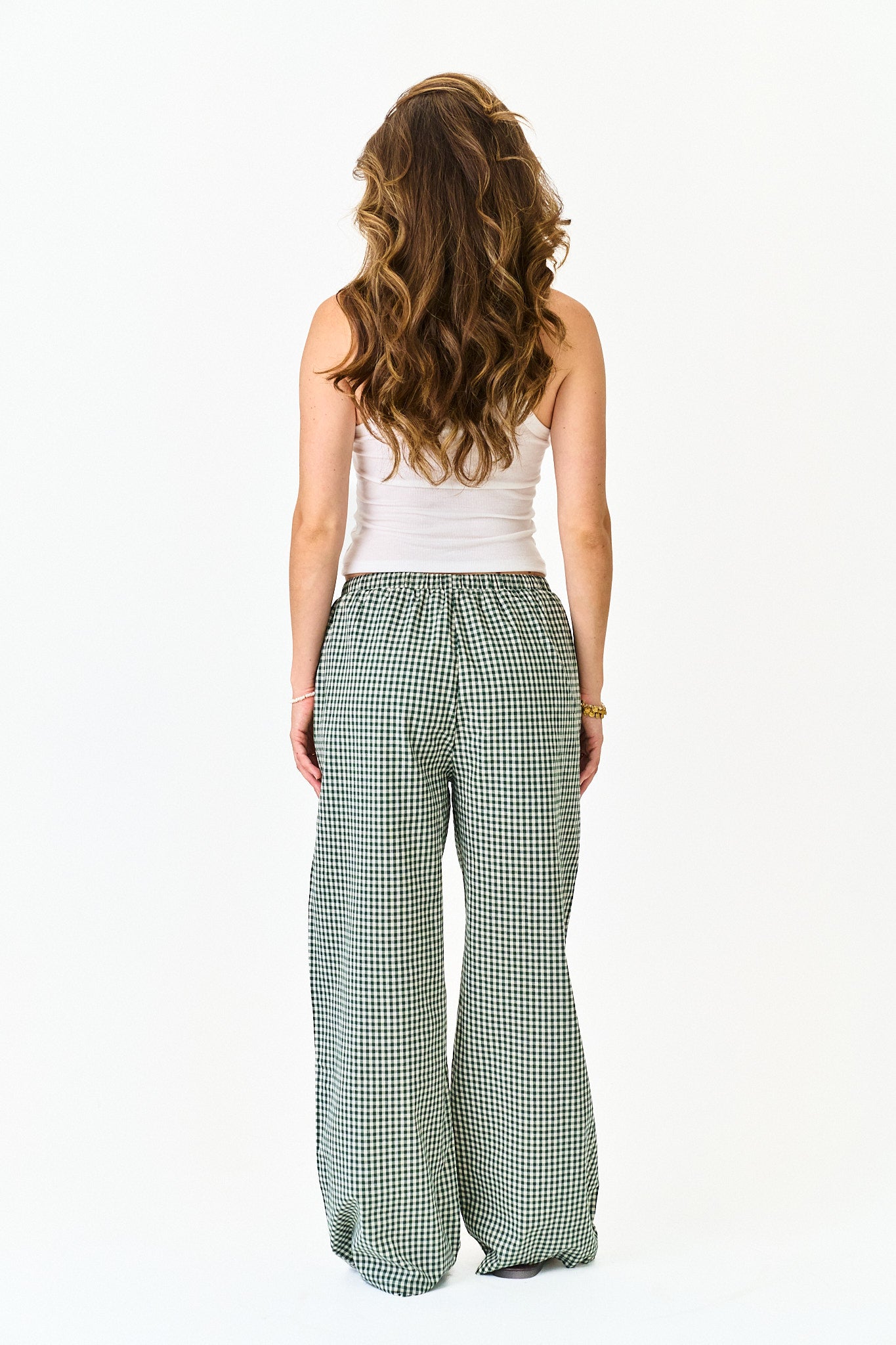 Woman wearing a white top and green checkered pants on a white background