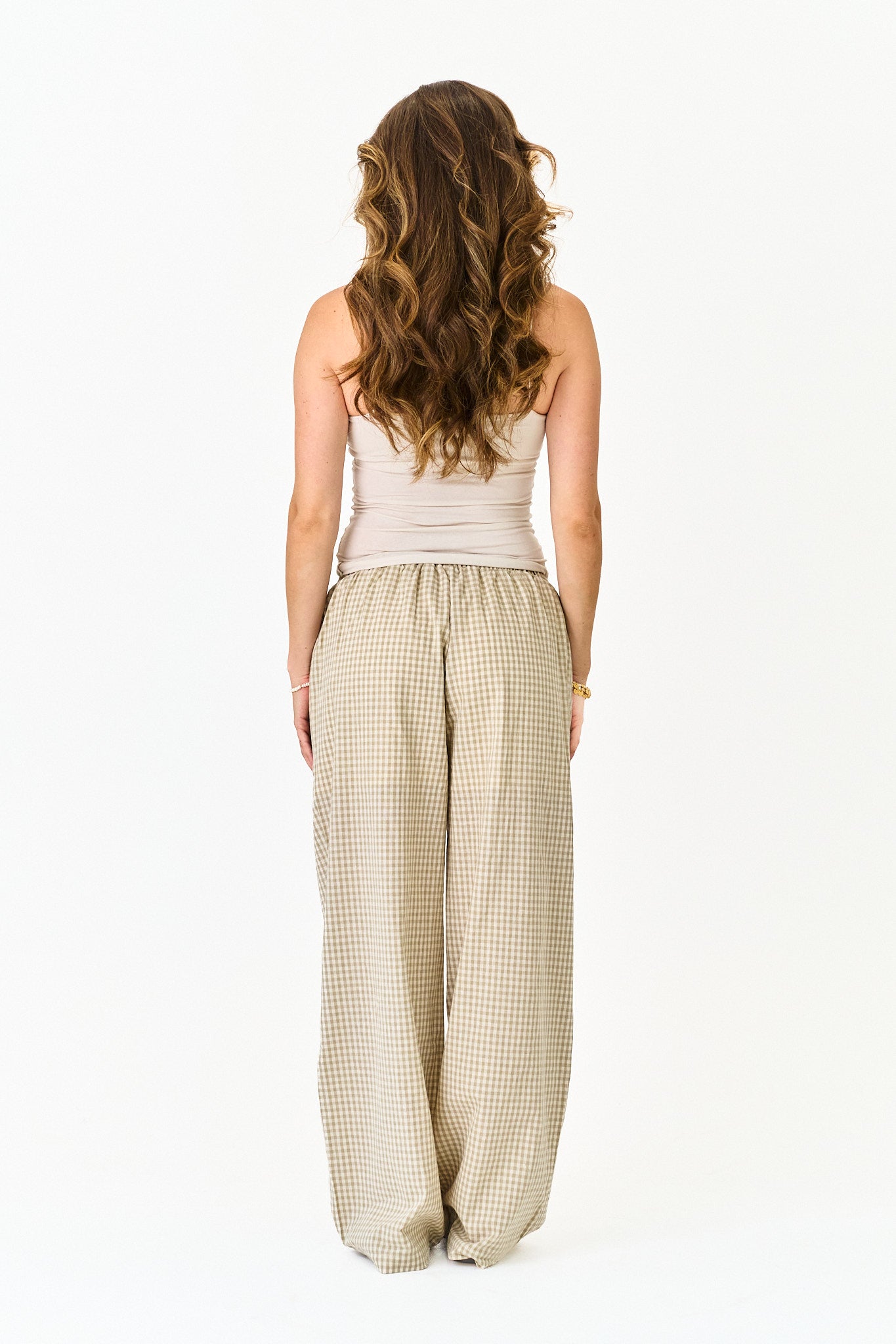 Woman wearing a sleeveless top and checkered pants on a white background