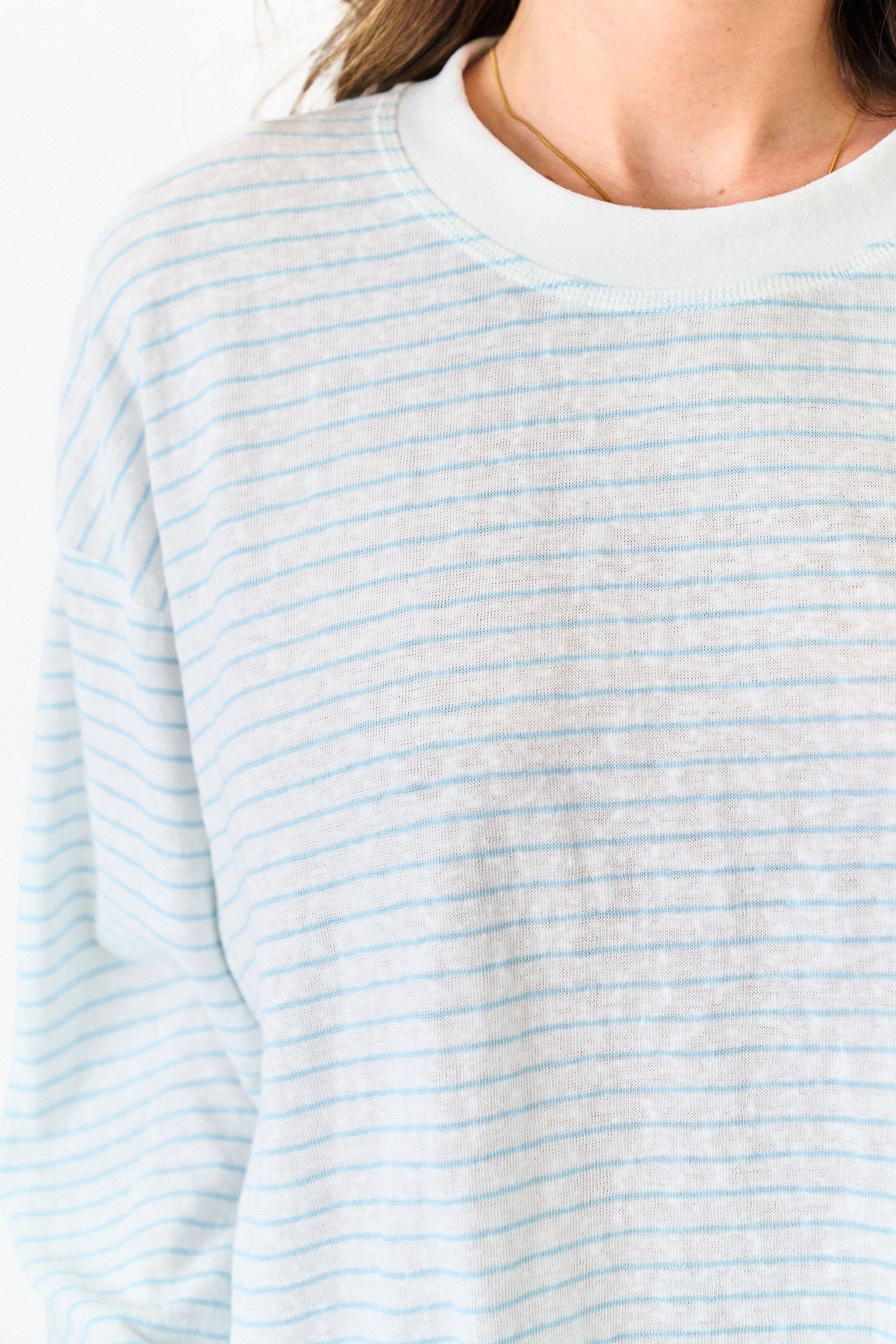 Close-up of a person wearing a light blue and white striped shirt.