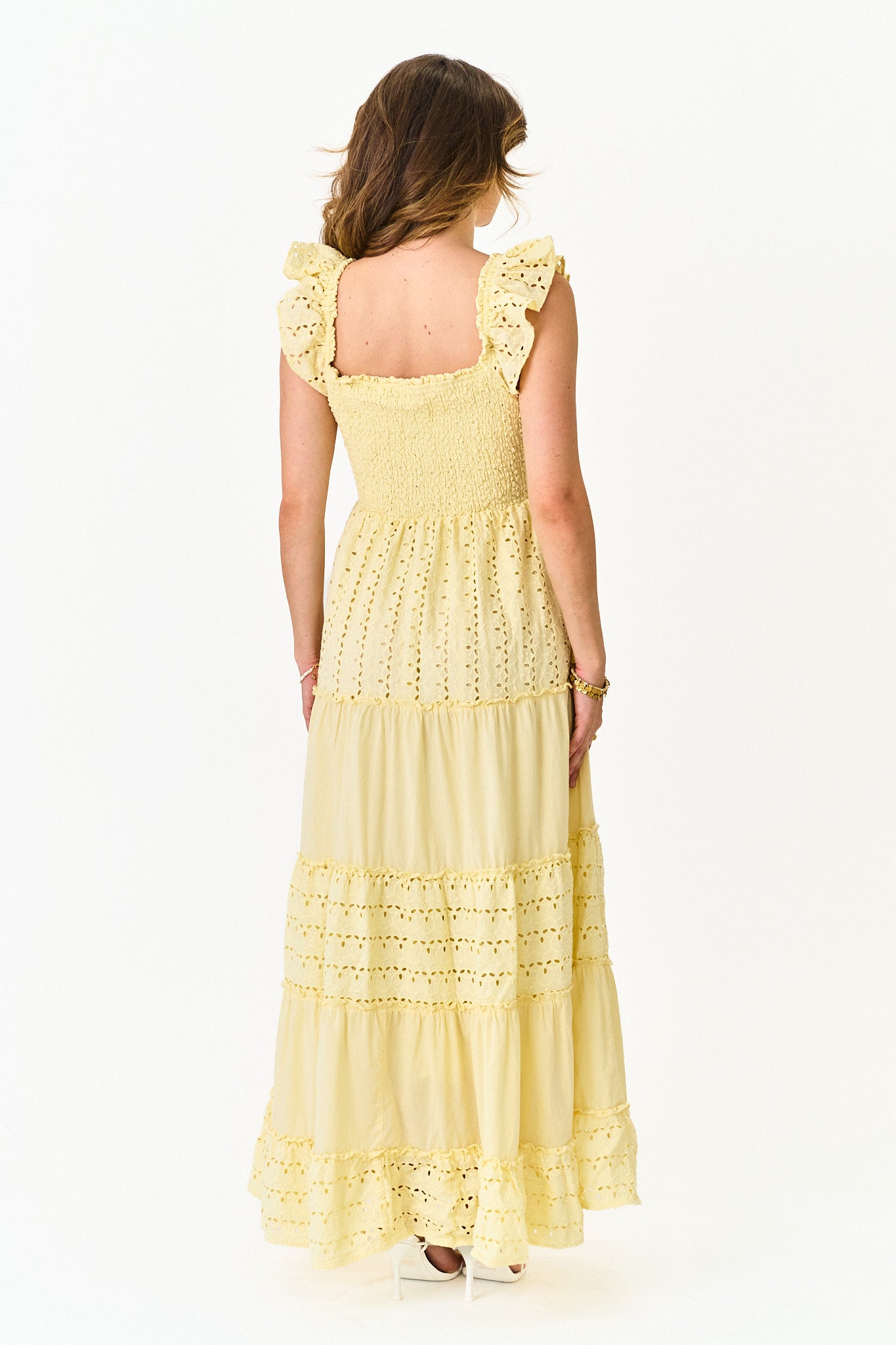 Woman wearing a yellow dress with ruffled sleeves on a white background