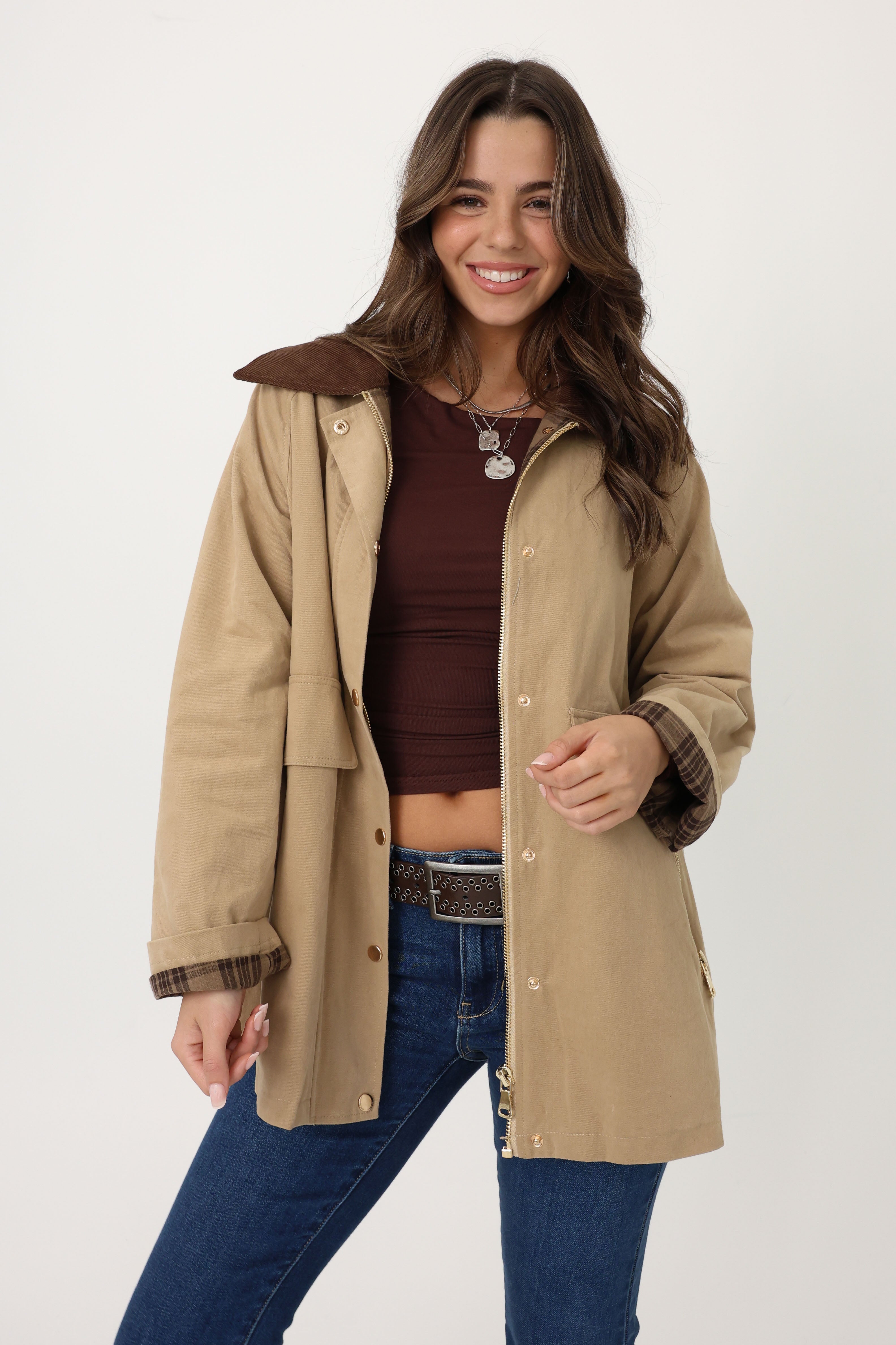 Woman wearing a beige coat with brown trim on a white background