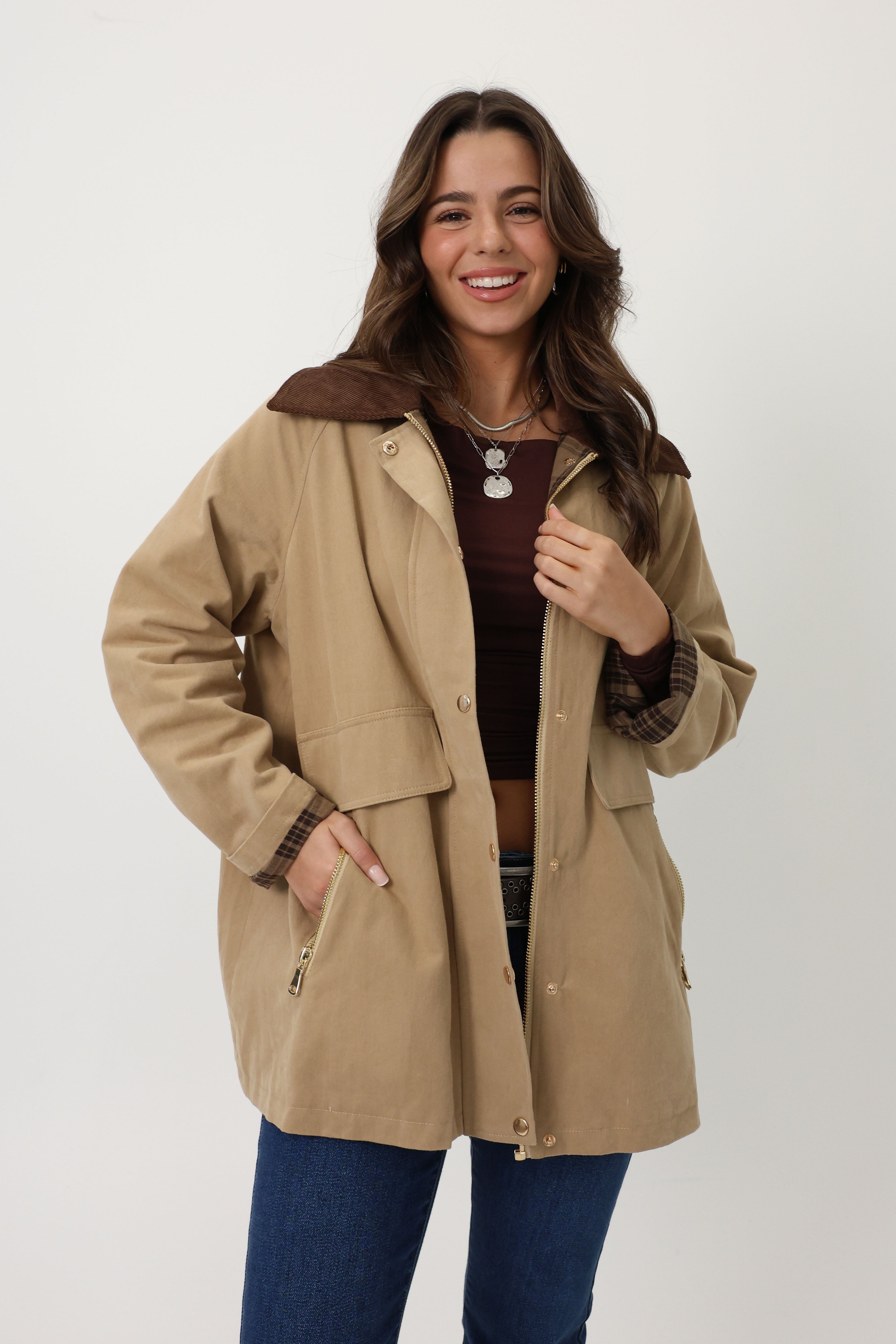 Woman wearing a beige coat with brown trim on a white background