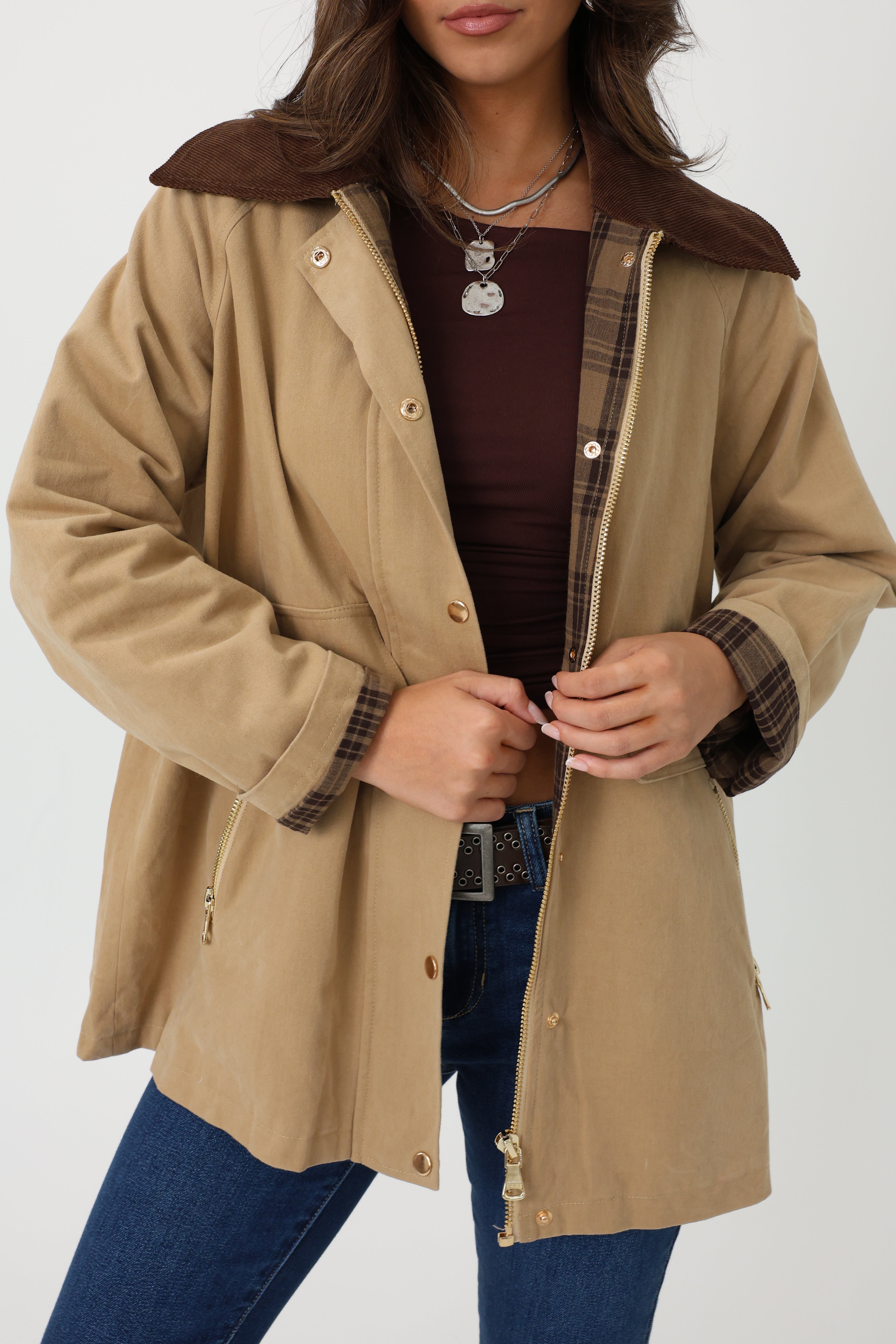 Person wearing a beige coat with brown lining on a white background
