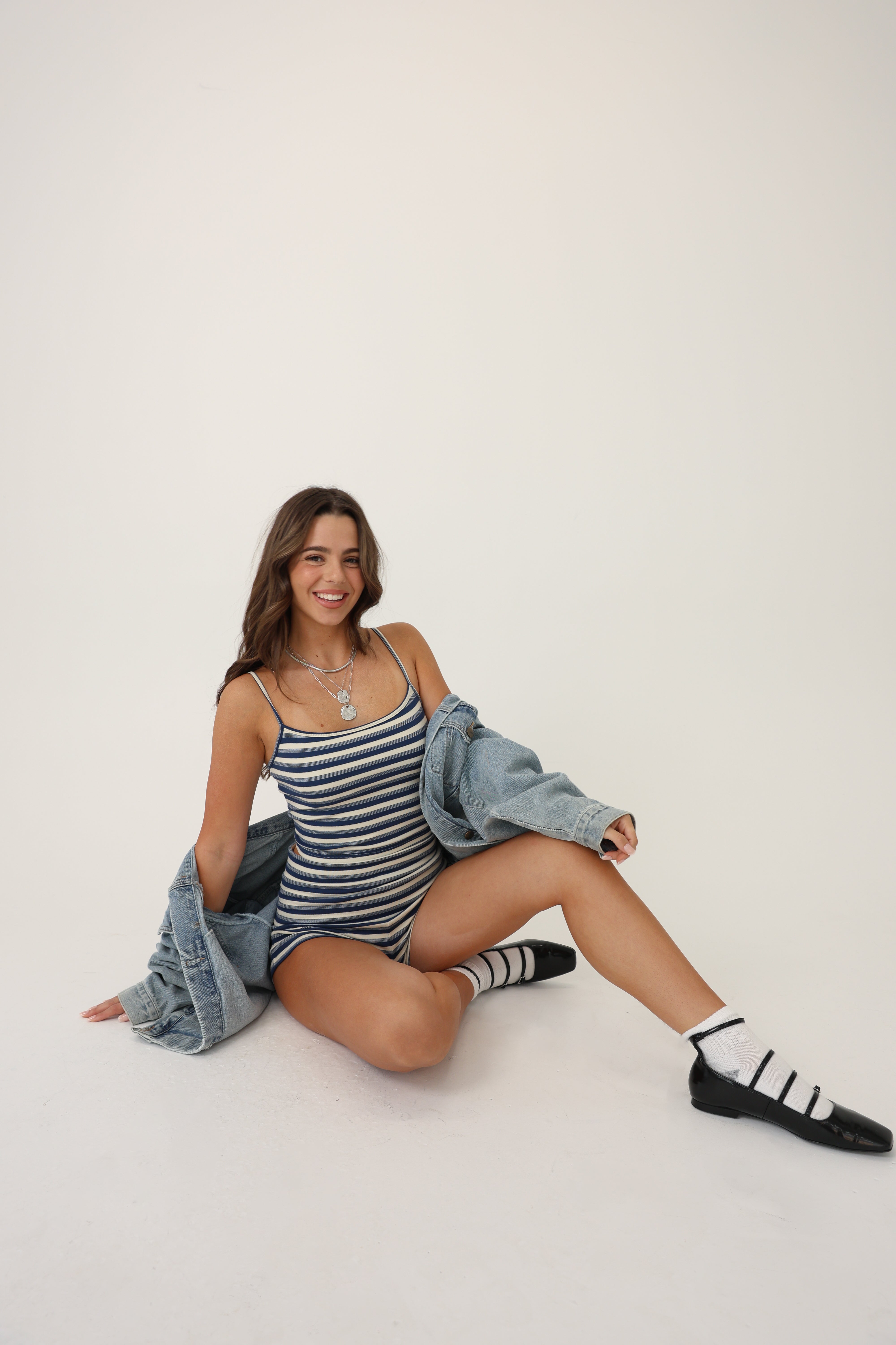 Person wearing a blue and white striped tank top and shorts set with denim jacket