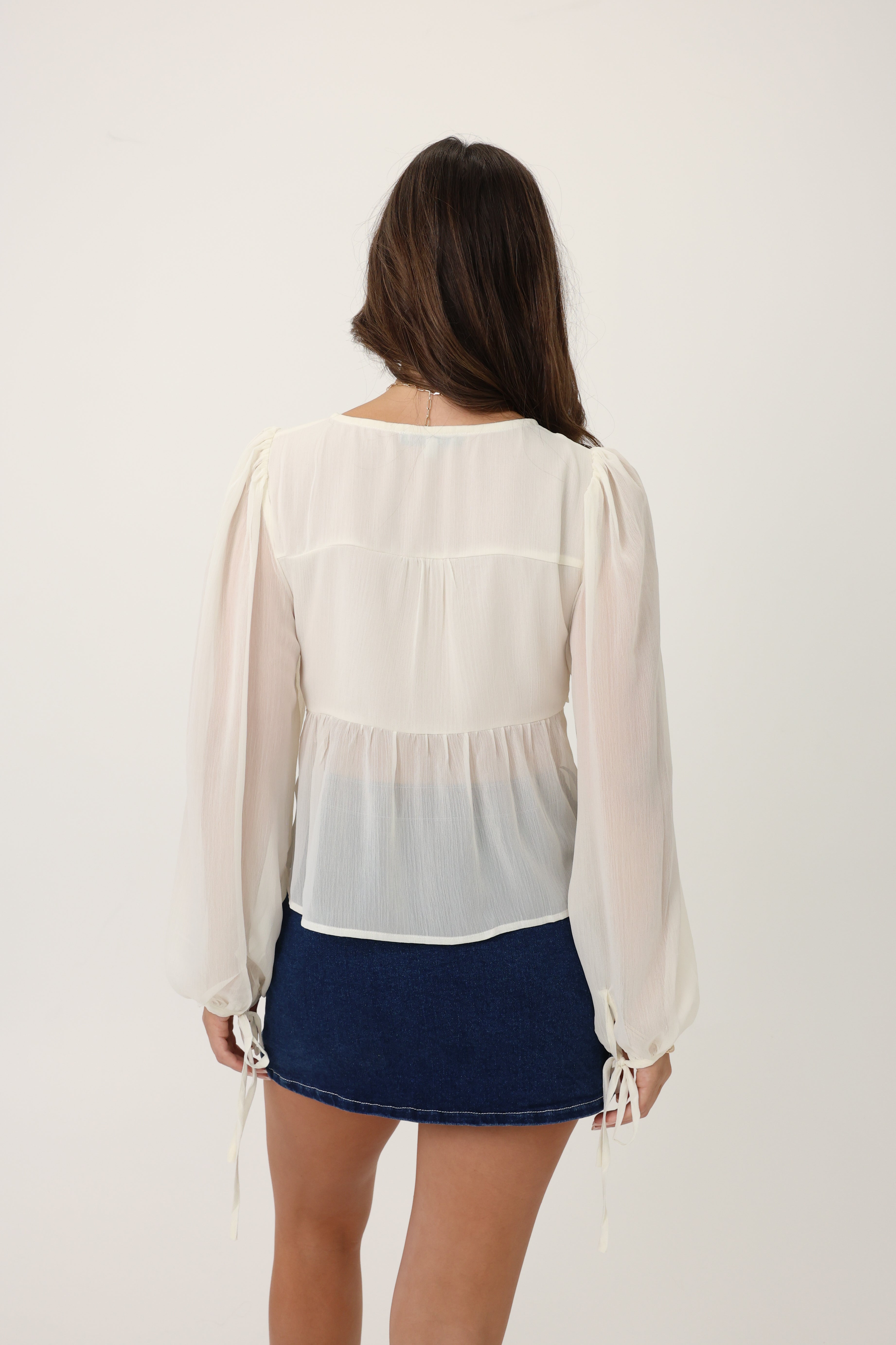 Woman wearing a white blouse with a gradient effect and a navy skirt on a white background