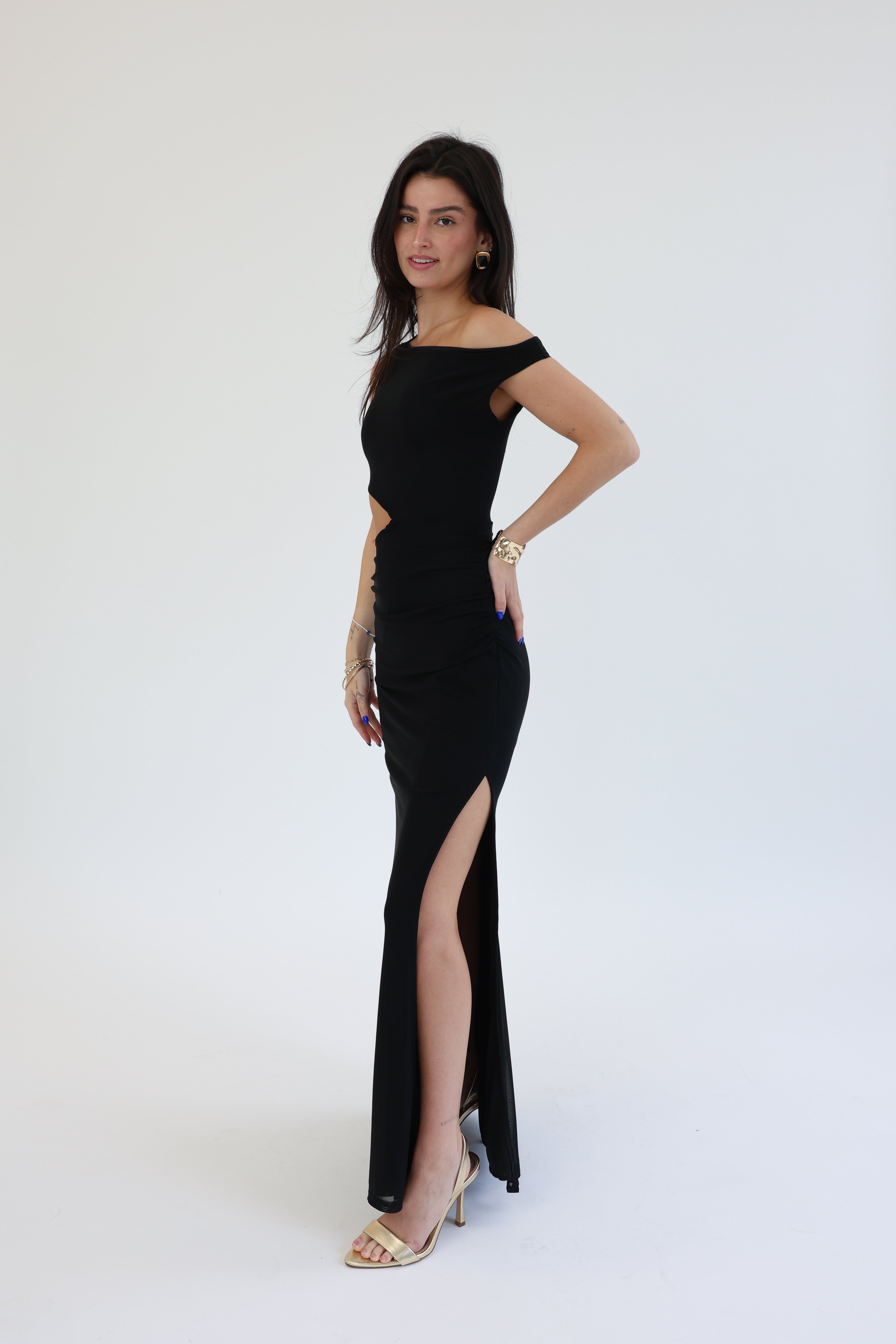 Woman wearing a black evening gown with a high slit on a white background