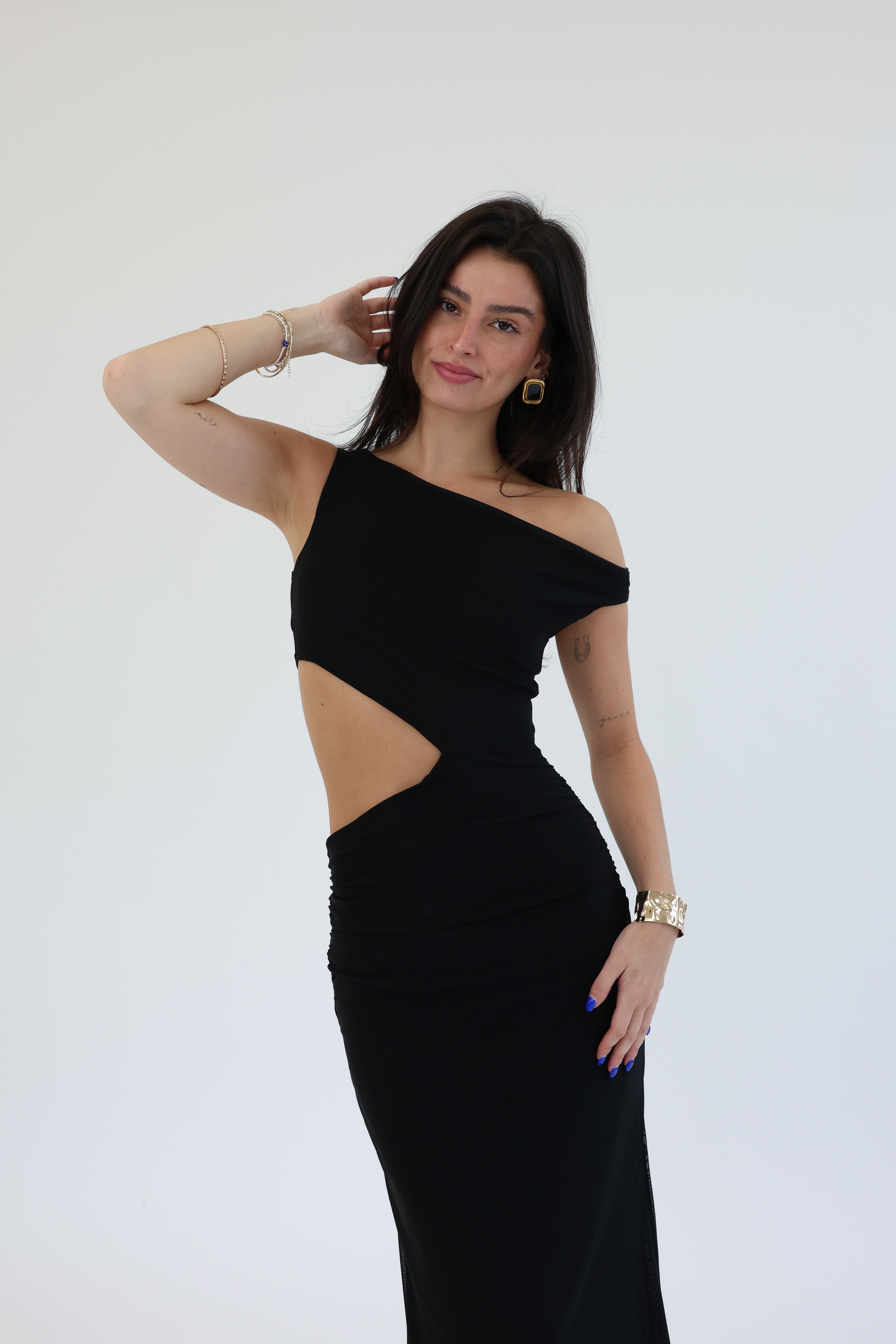 Woman wearing a black one-shoulder dress with cut-out design on a white background