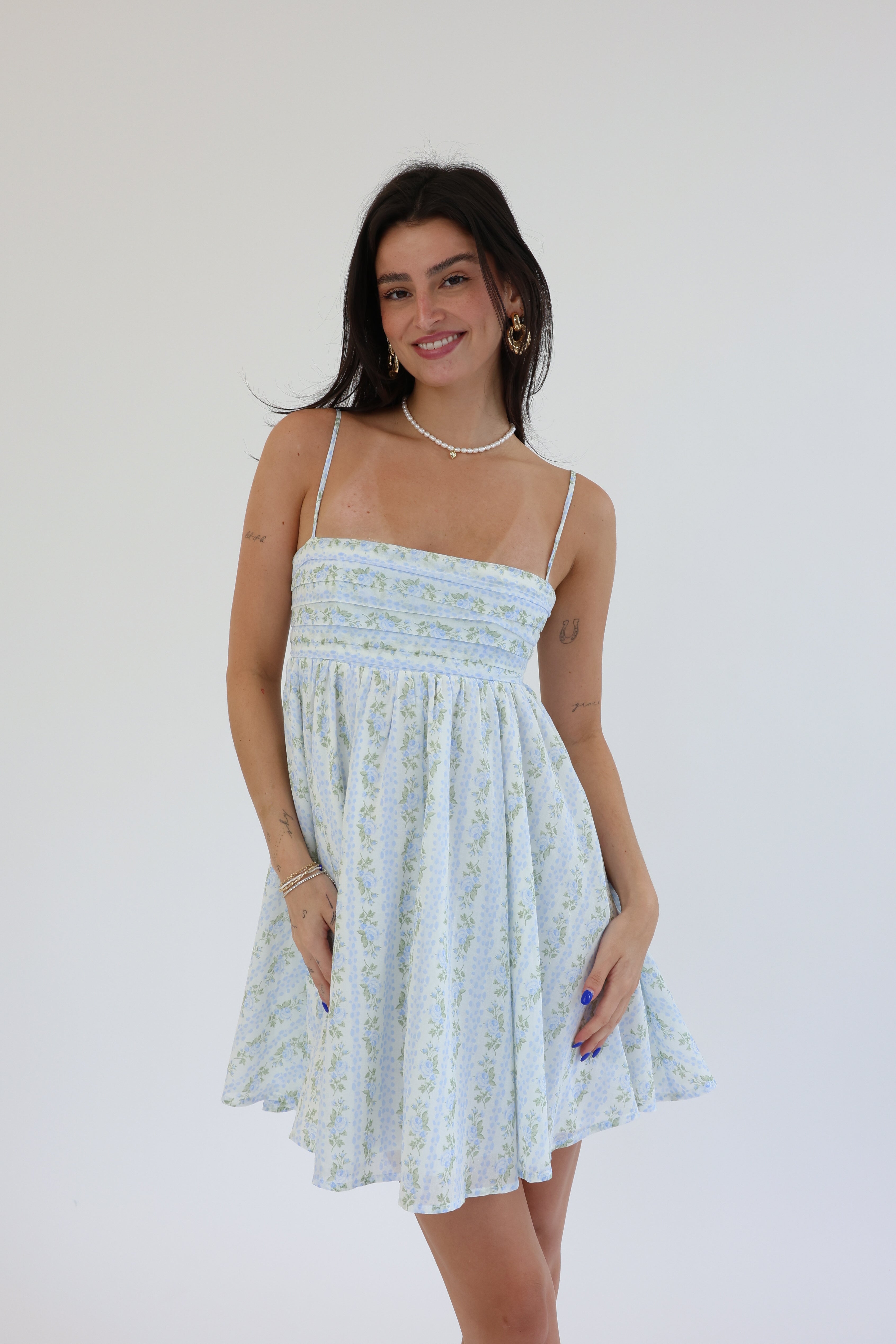 Woman wearing a light blue floral dress against a white background
