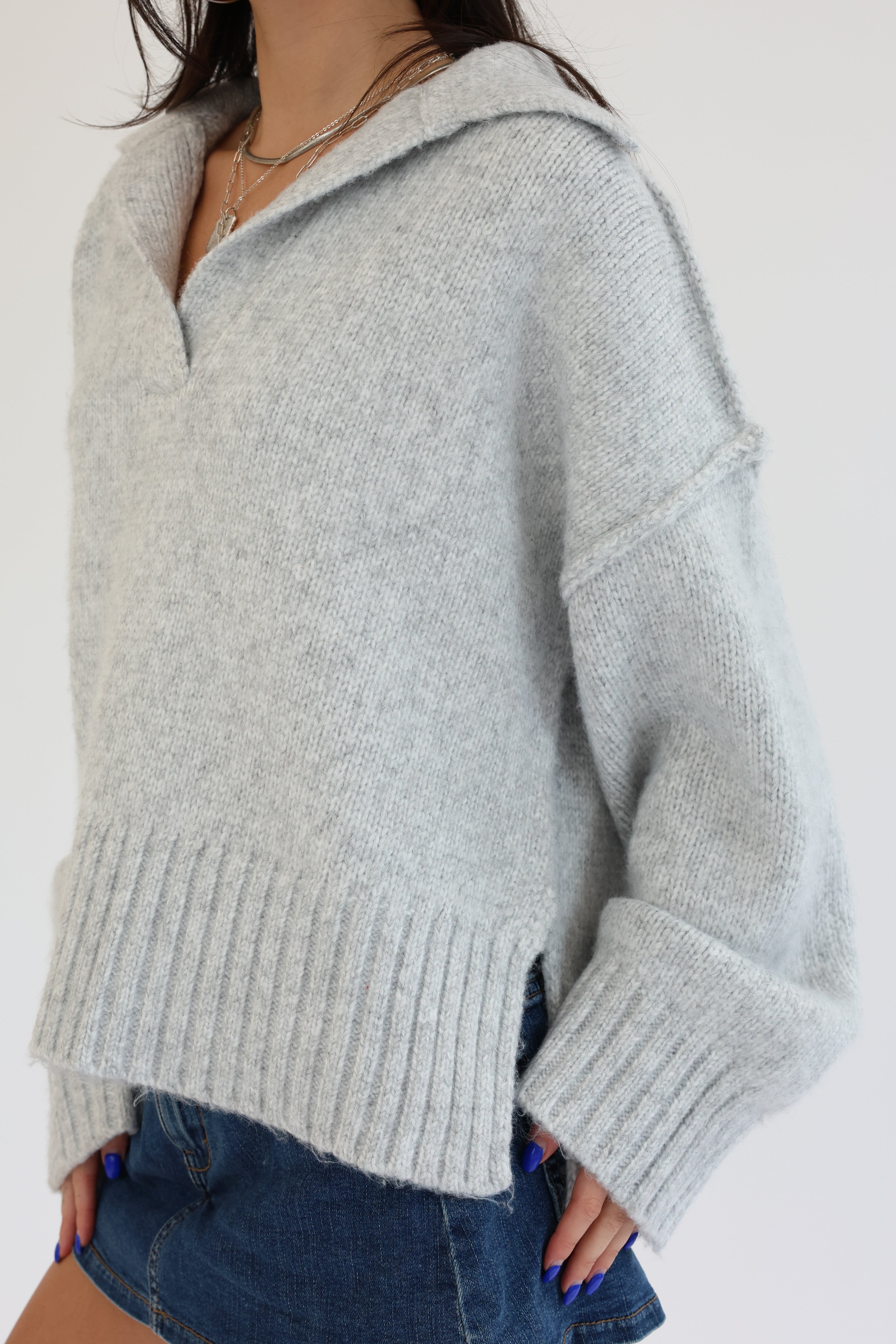 Person wearing a light gray sweater with a white background