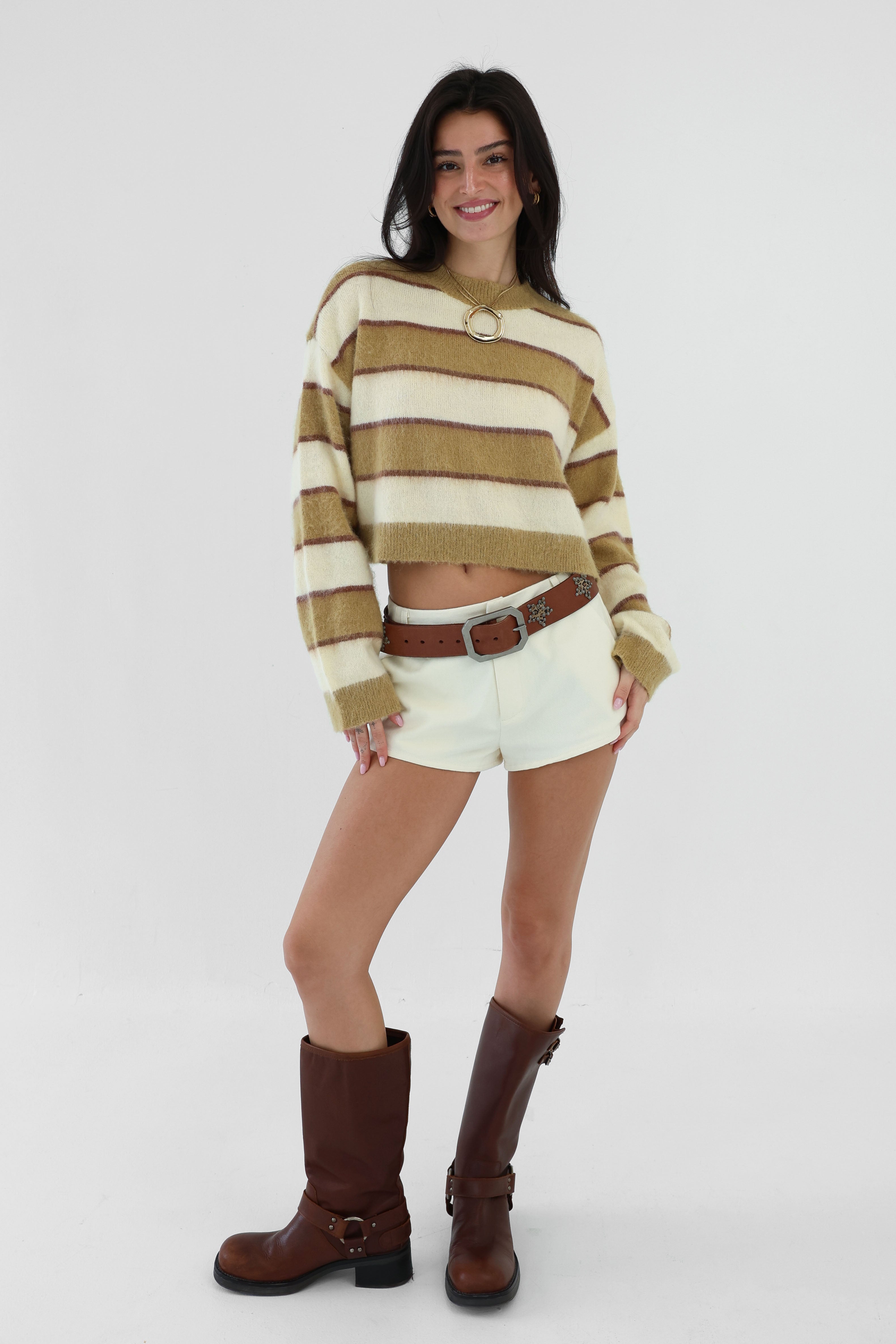 Woman wearing a striped sweater, shorts, and boots on a white background