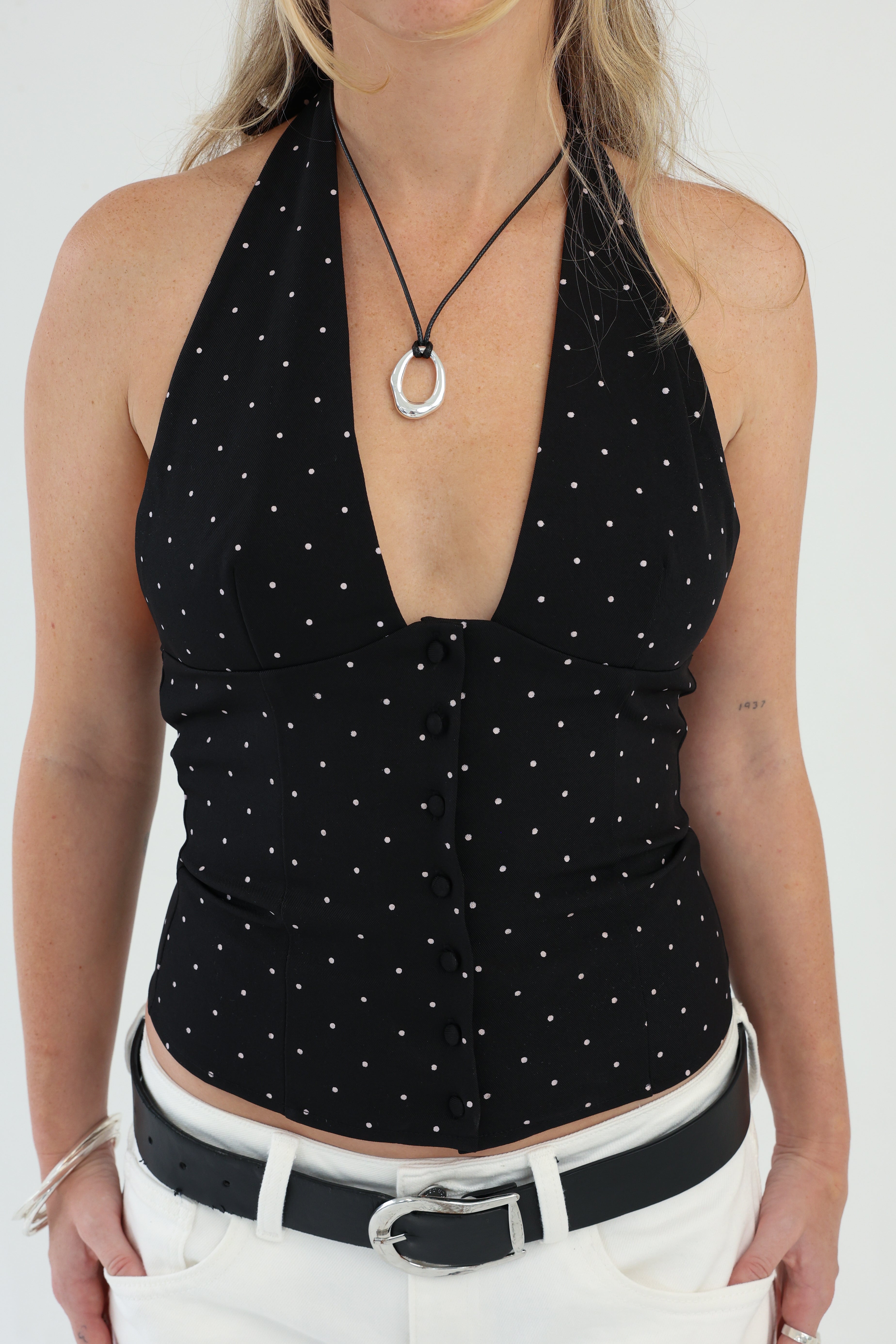 Black polka dot halter top worn by a person on a white background