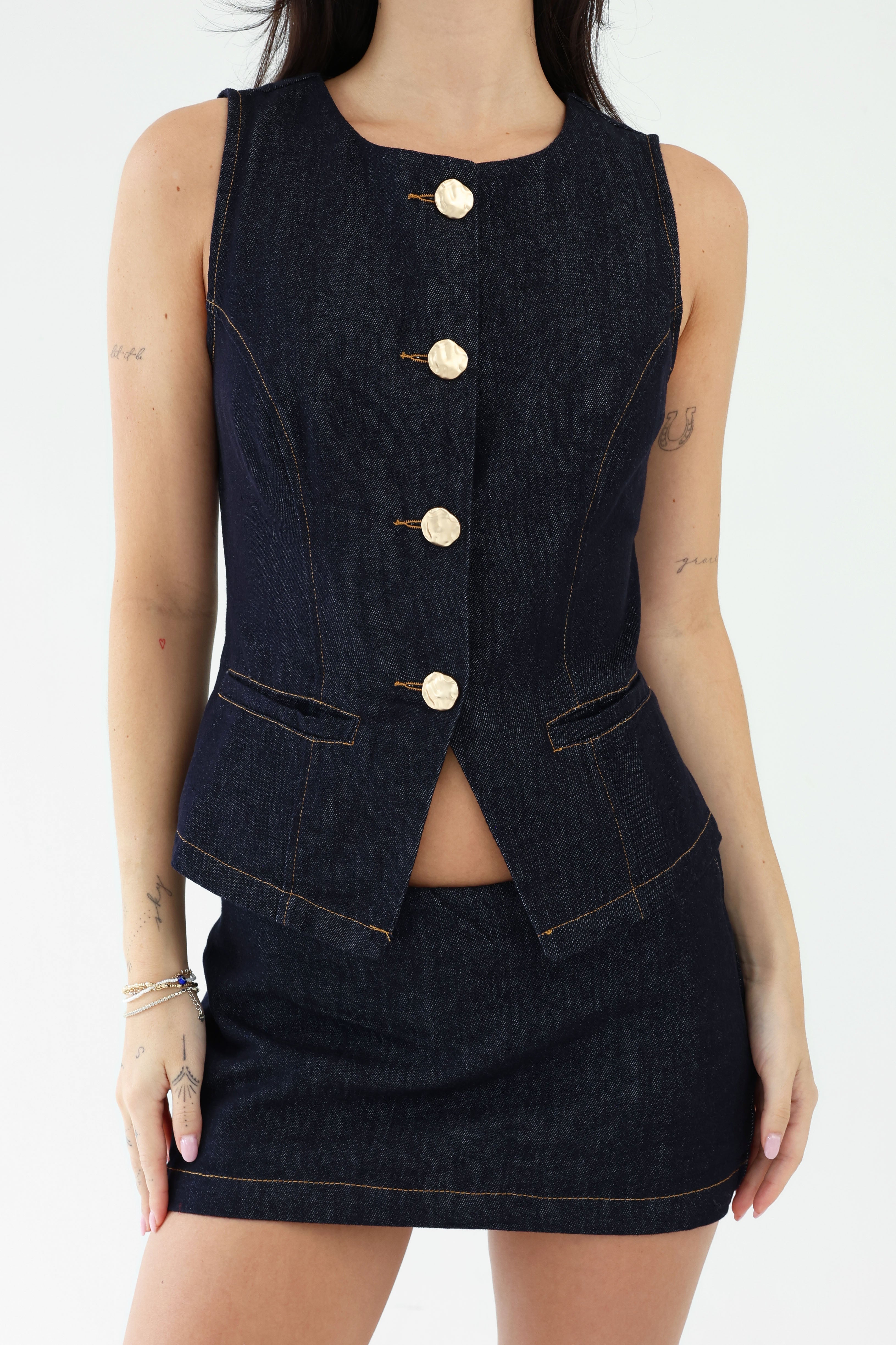 Denim vest with gold buttons over a denim skirt on a white background