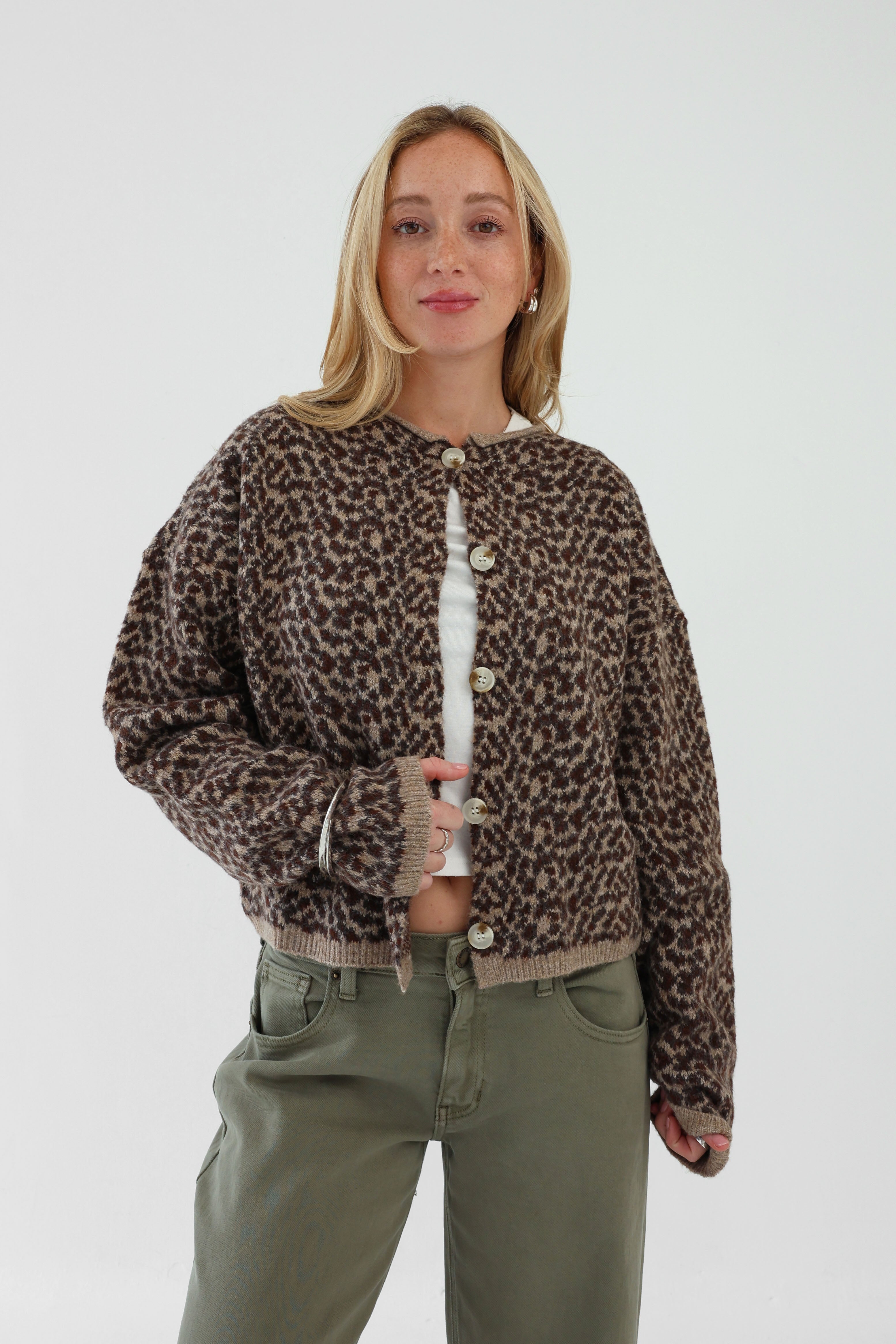 Person wearing a leopard print jacket with white buttons on a white background