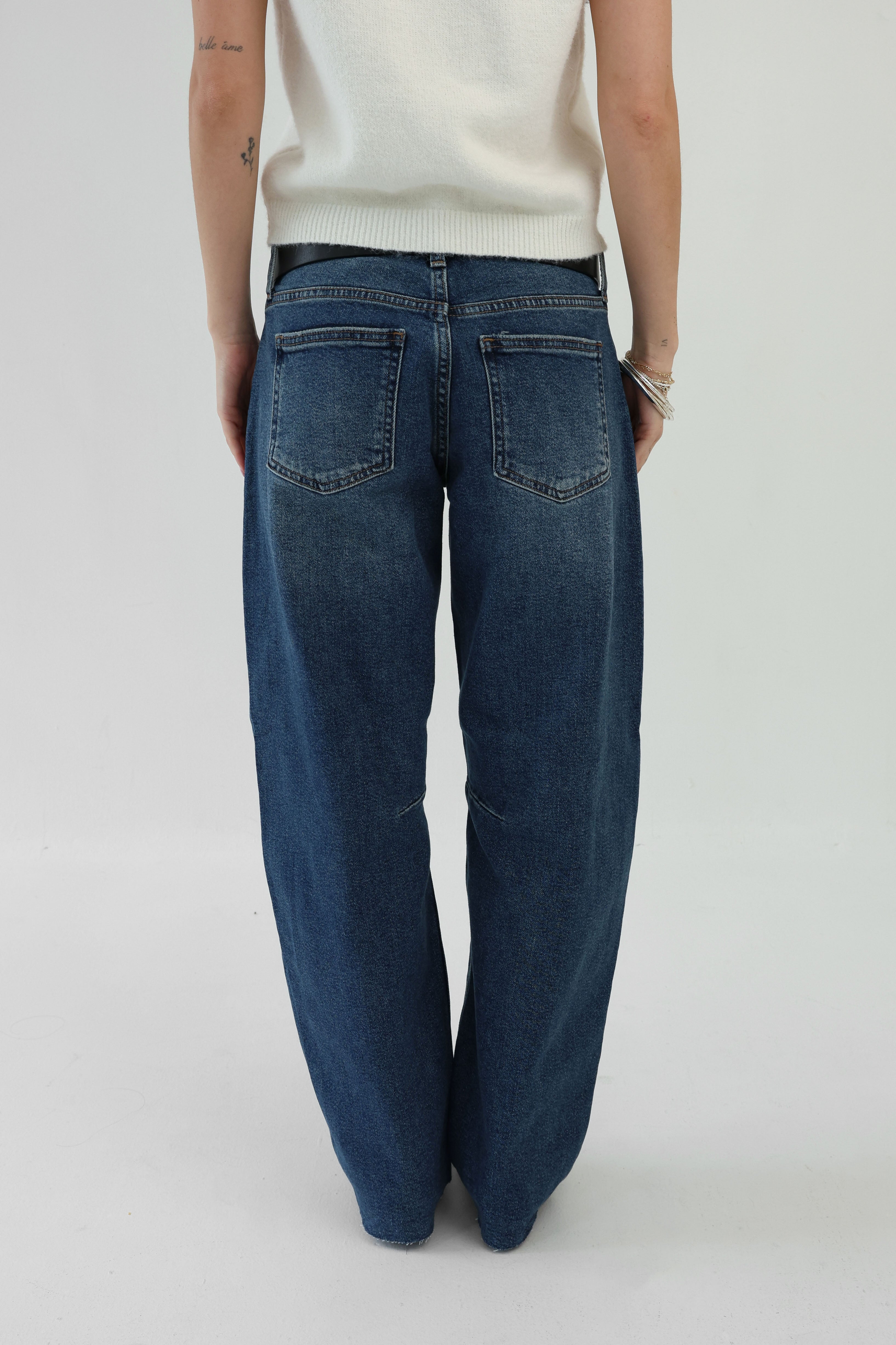 Person wearing blue jeans on a plain background