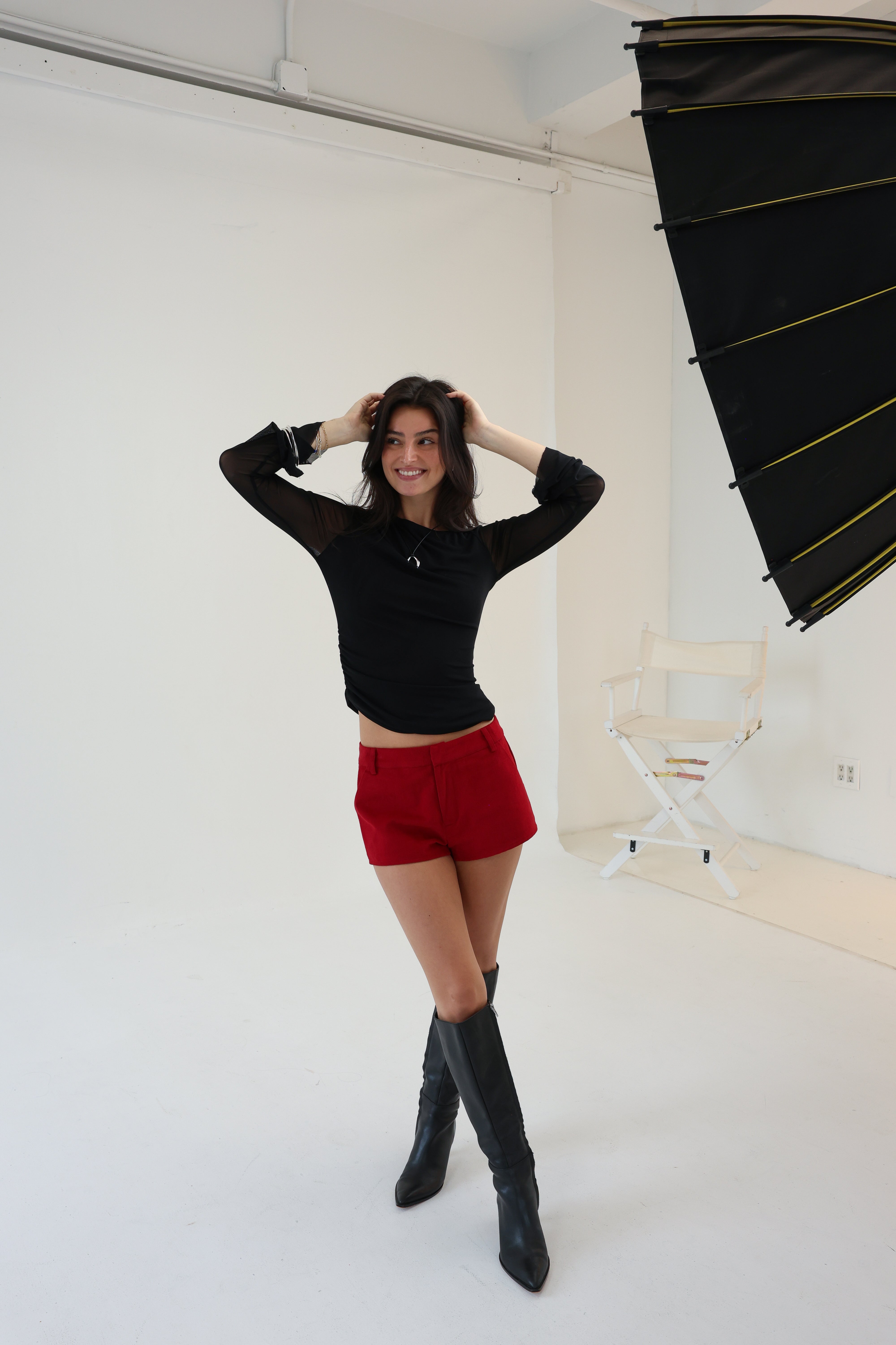 Woman posing in a studio setting with photography equipment.