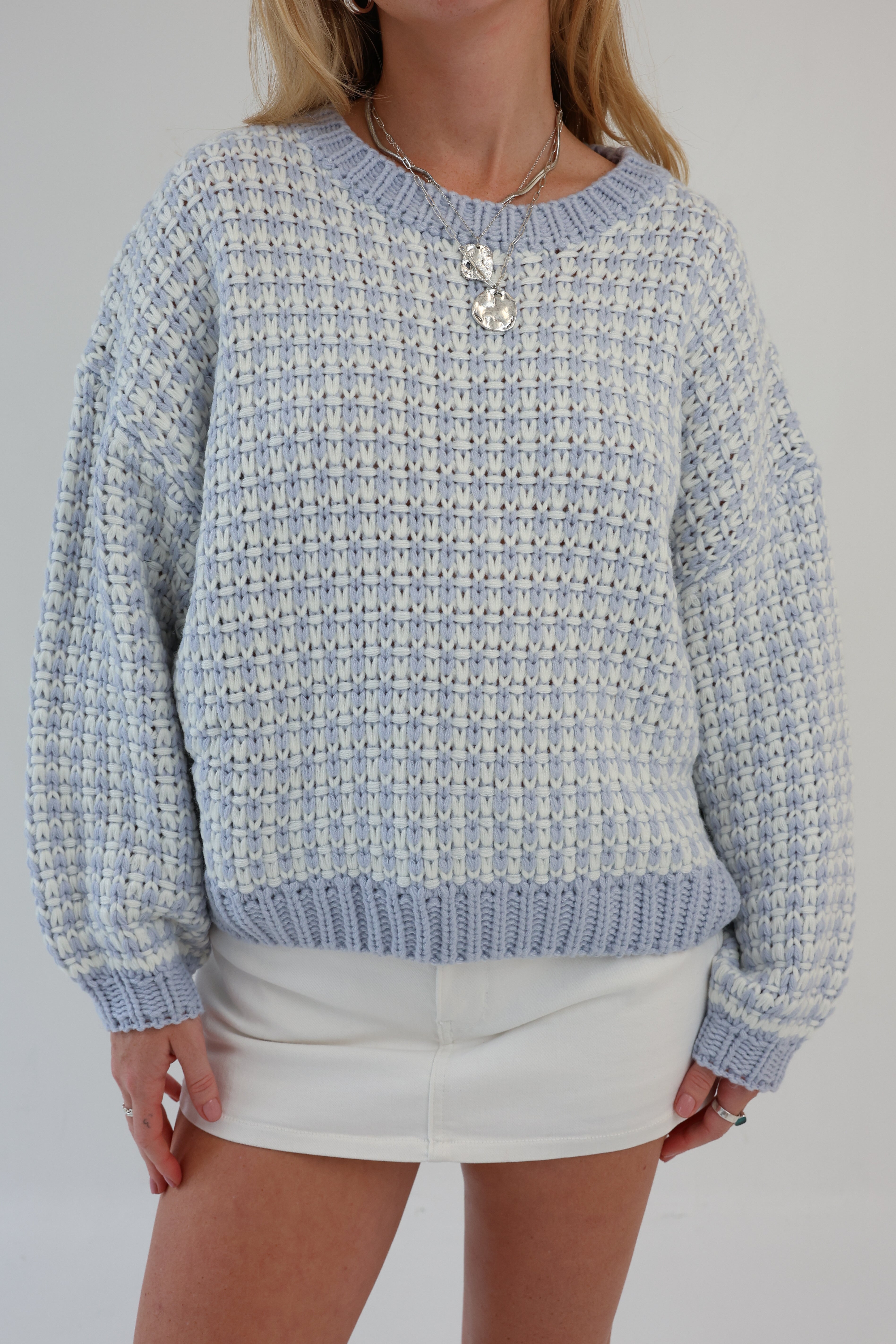 Person wearing a patterned blue and white sweater with a plain background