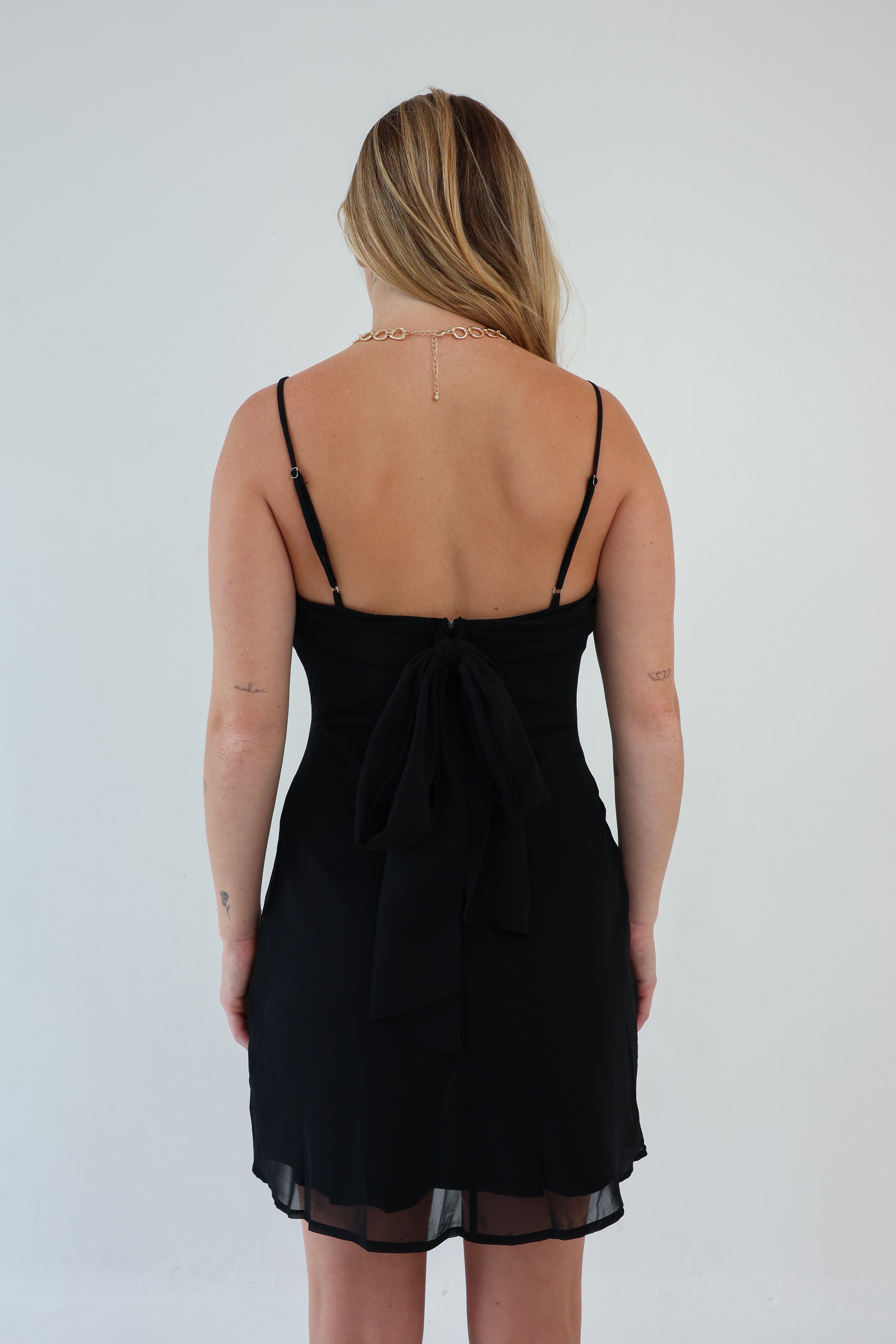 Black dress with thin straps worn by a person on a white background