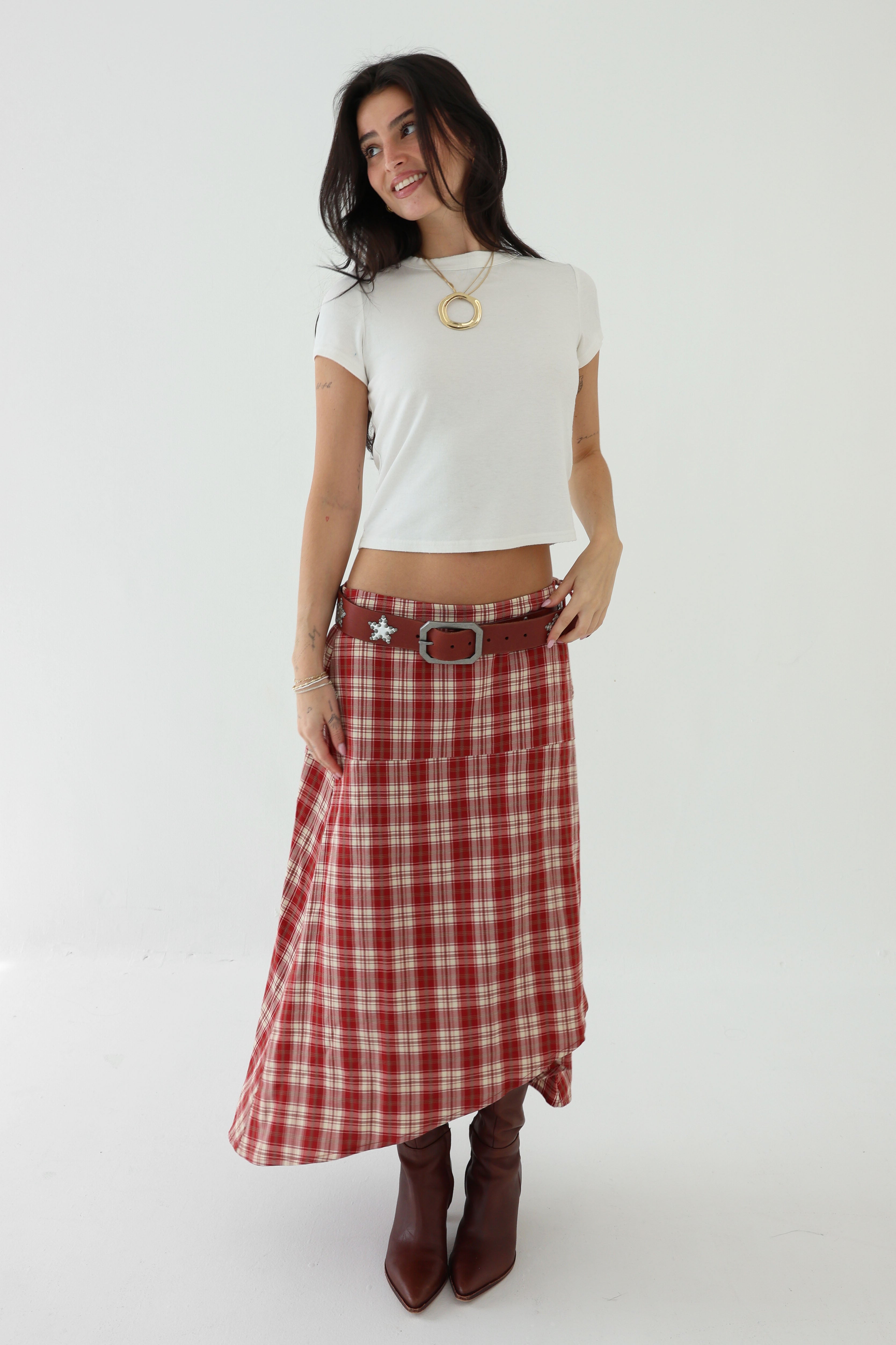 Woman wearing a white crop top and red plaid skirt on a white background