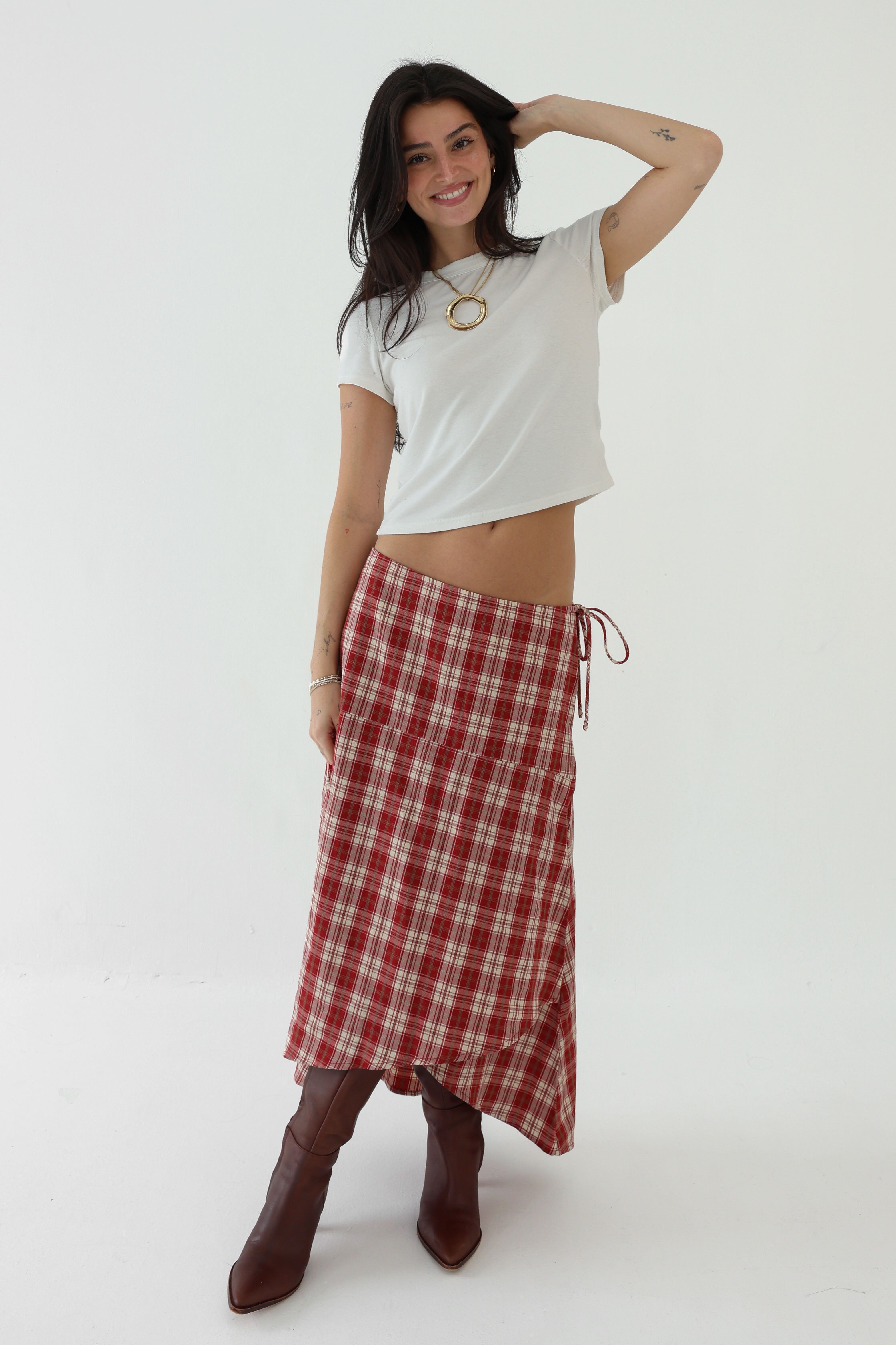 Woman wearing a white crop top and red plaid skirt on a white background